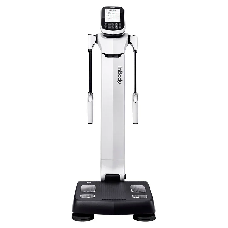 An InBody body composition analysis machine with a digital screen, two handles, and a platform for standing, used for health assessments.