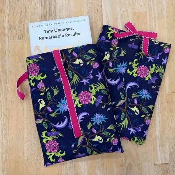 Two dark purple and floral book sleeves with pink ribbon ties