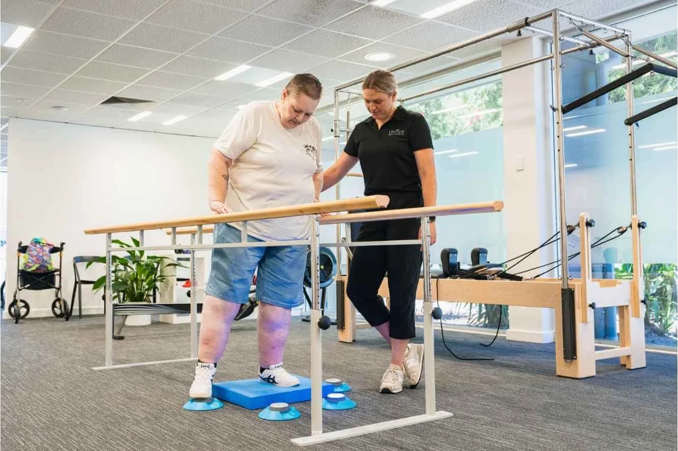 Physiotherapist assisting aged care client using parallel bars at Findon clinic