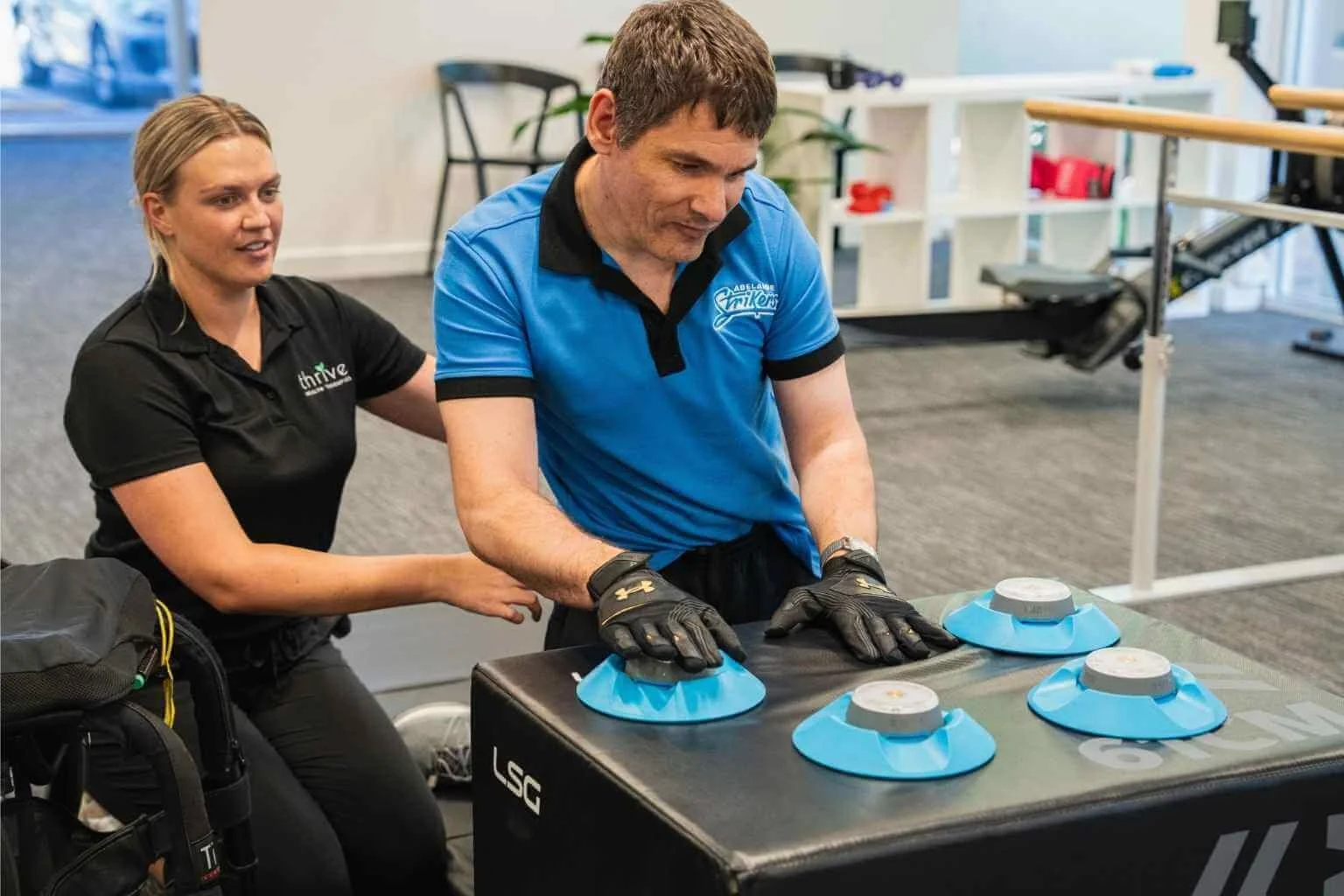 Physiotherapist smiling assisting client who is using neurological rehabilitation equipment at our Findon clinic