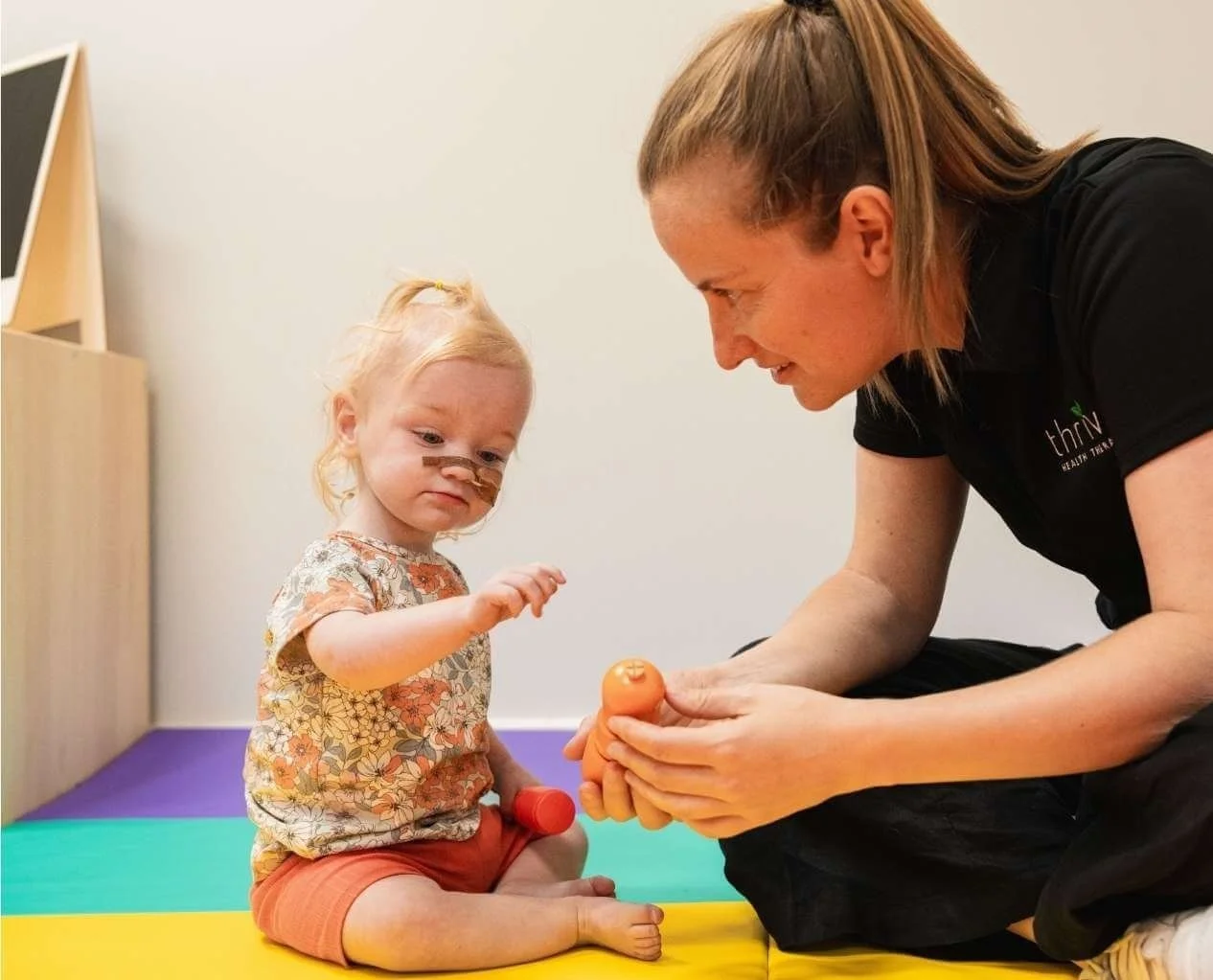 Paediatric speech therapist working with young child with a nasogastric tube during a swallowing assessment
