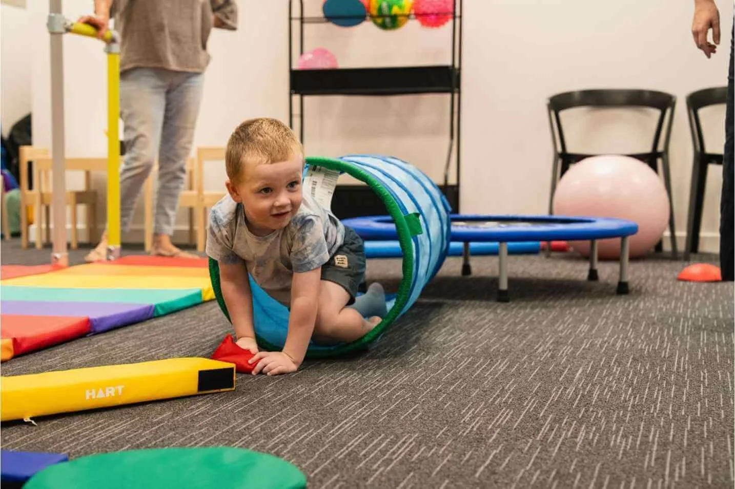Young child crawling out of a play tunnel during a children's occupational therapy session at our Findon clinic