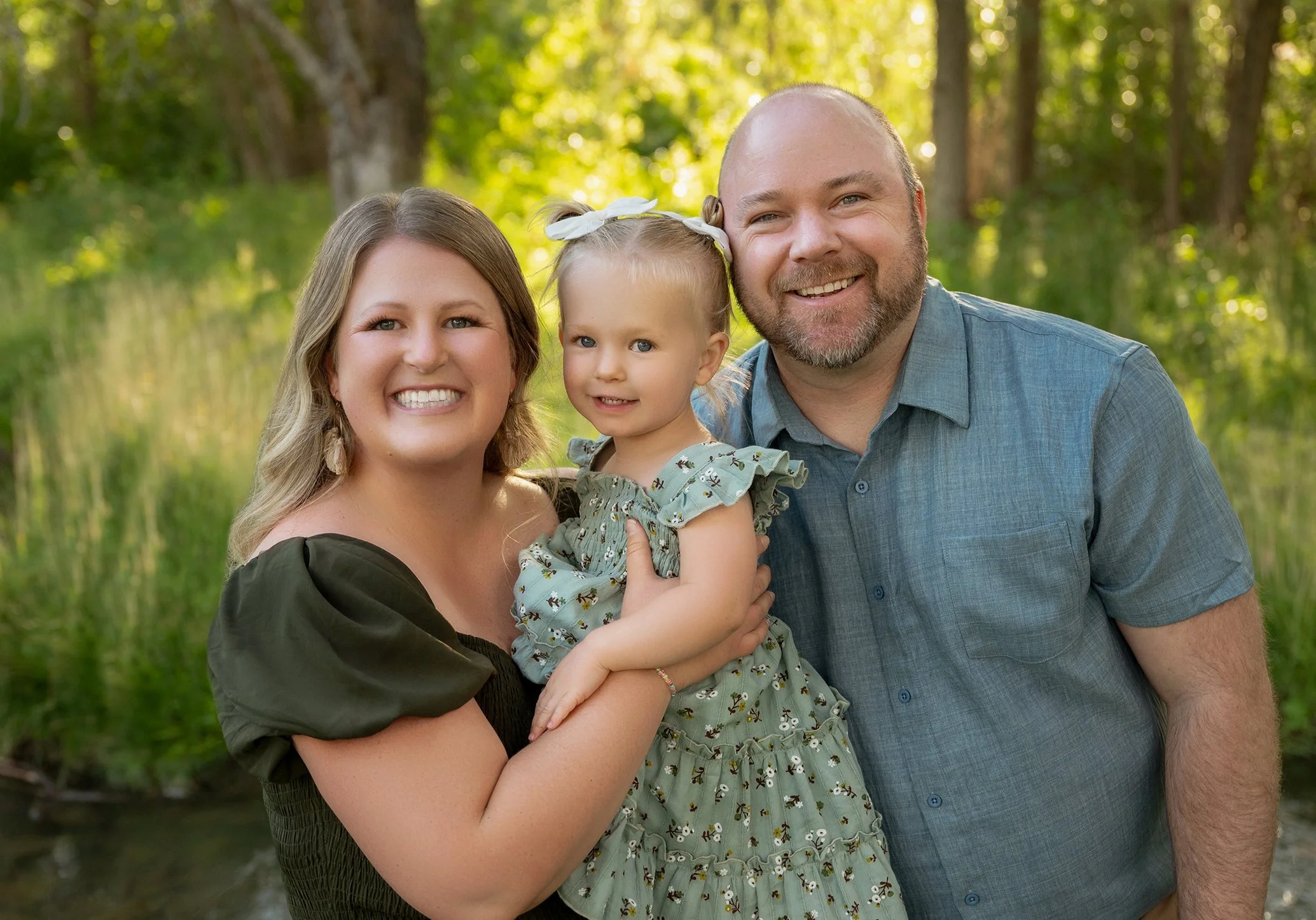 a cute family holding their toddler smiles for Danny Lemaire