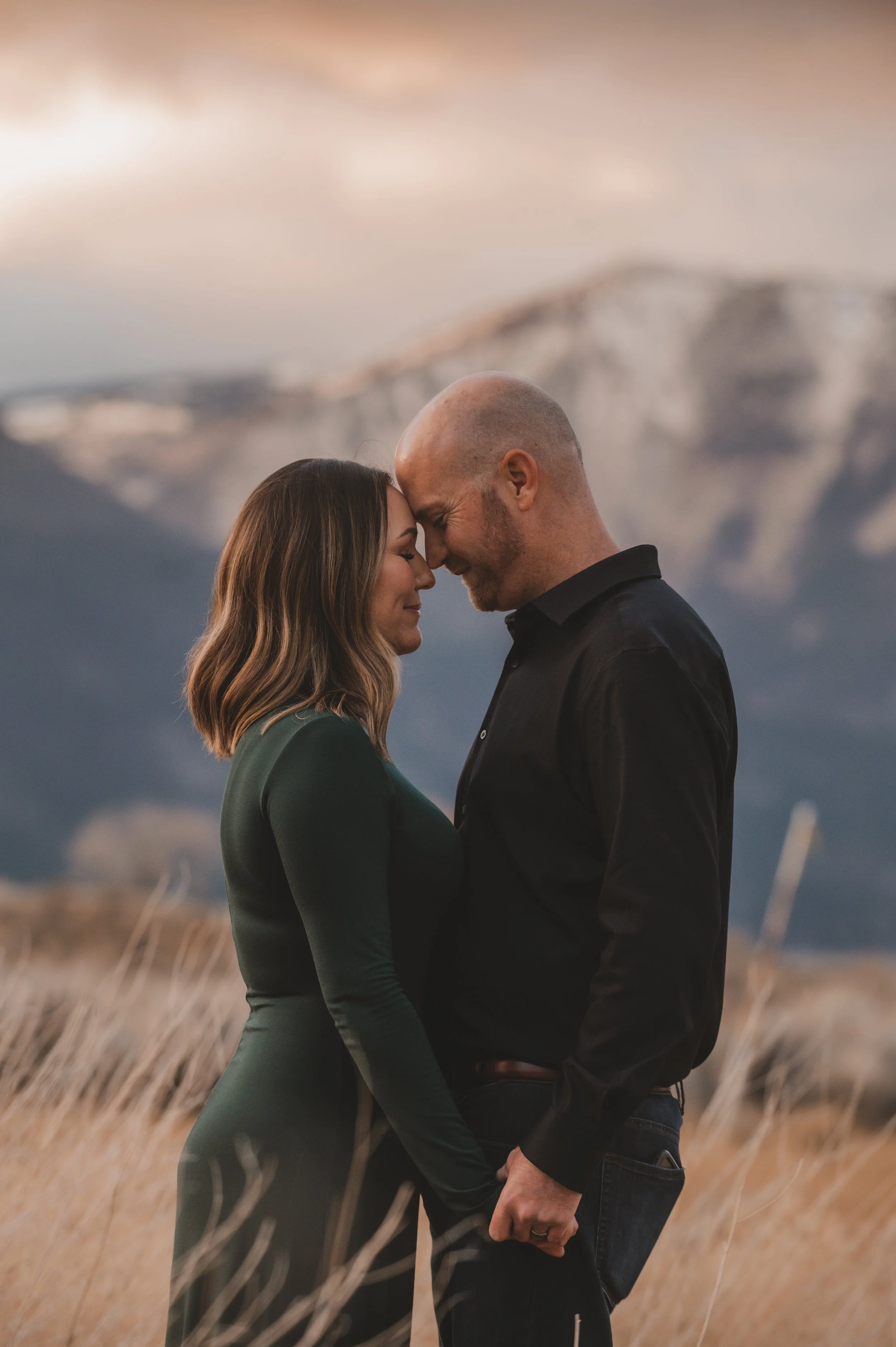 A couple press their heads together with the Washoe Valley mountains in the background