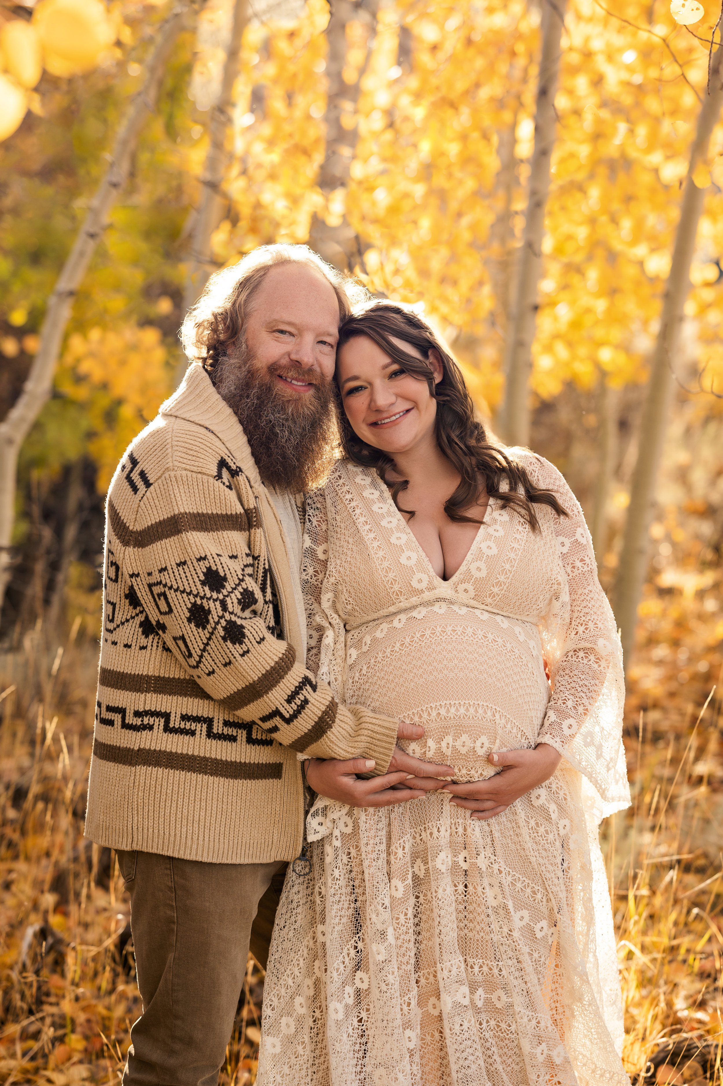 A sweet couple who is pregnant are smiling in Fall foliage in Reno Nevada 