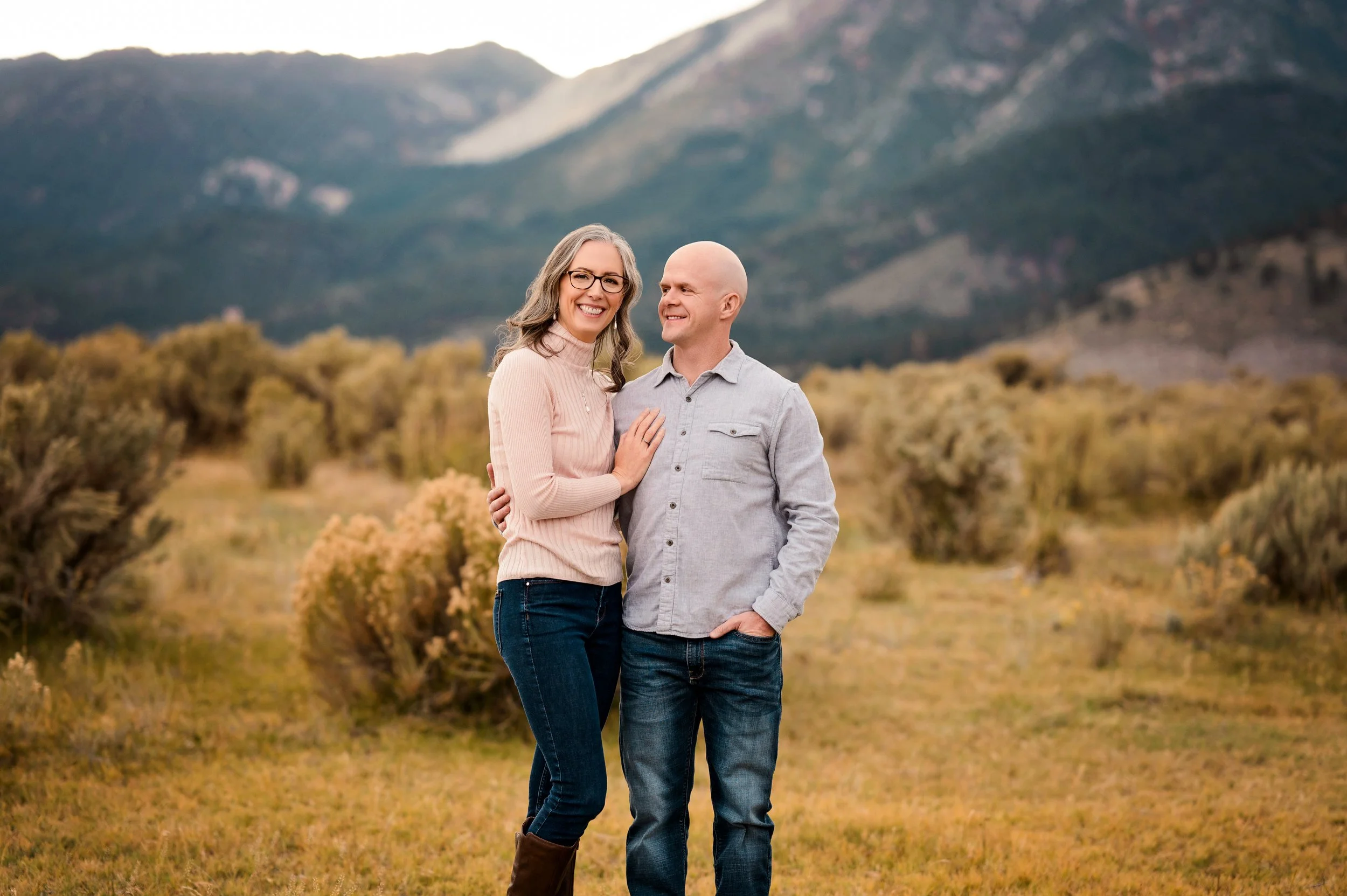 a couple smiles with the Washoe valley mountains in the background