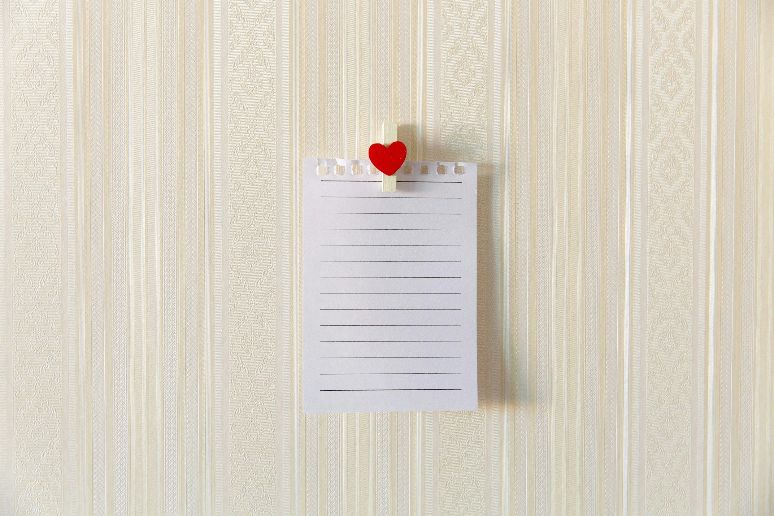 A small red heart clip holds up a tiny piece of paper