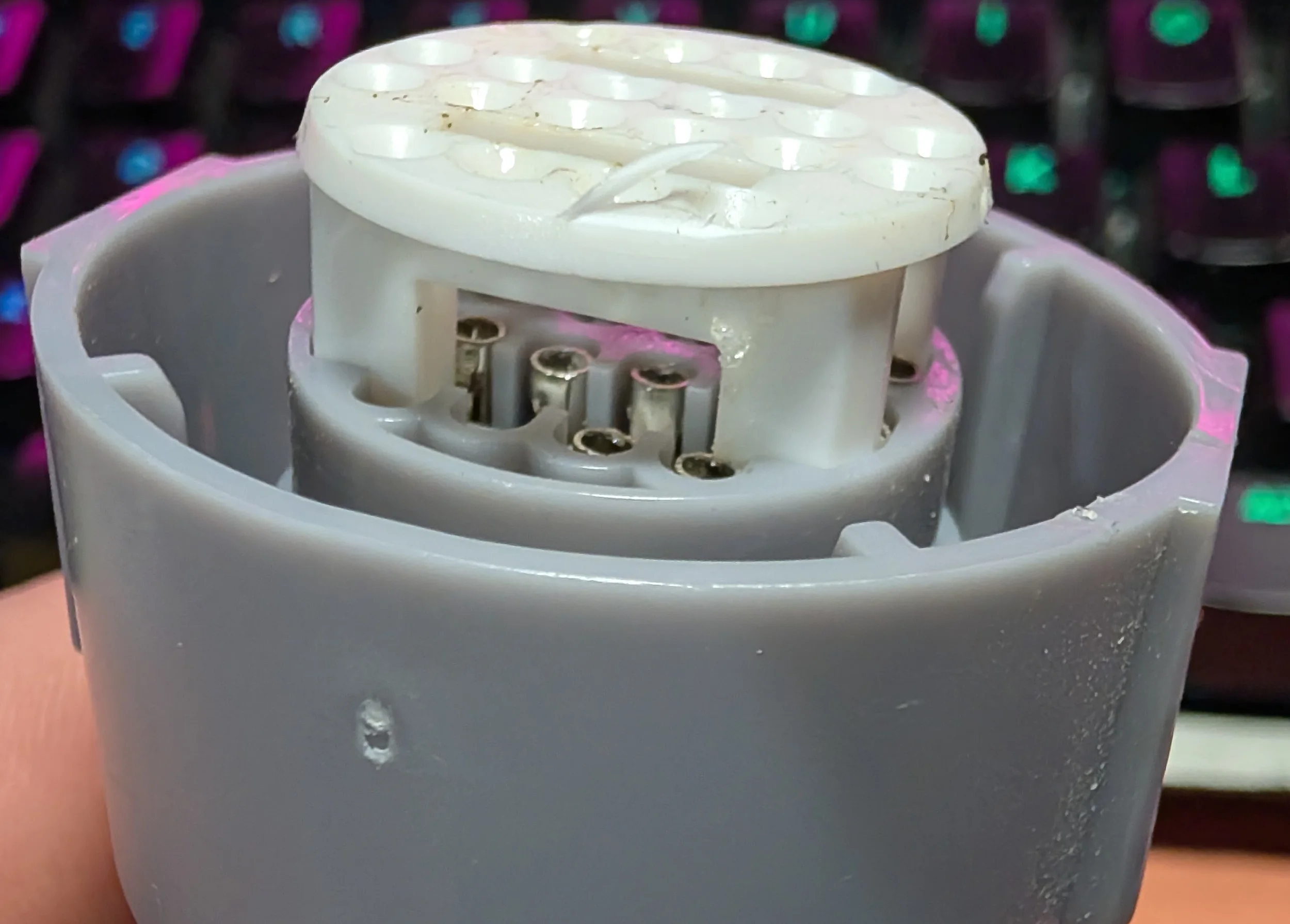 Releasing the secondary lock and pin retainer on a 4L60E round transmission connector to extract terminals for 4L80E wiring modifications.