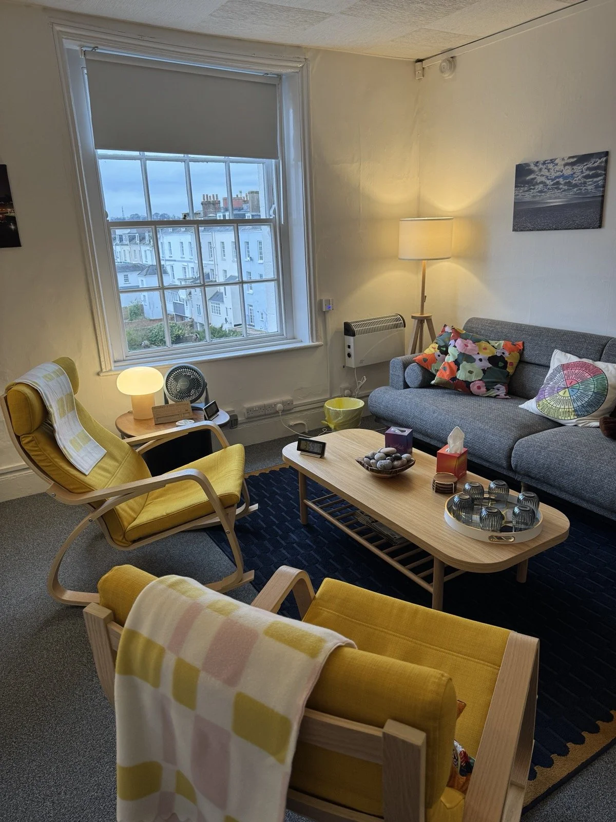 Jane's counselling room with 2 comfortable rocking chairs, blankets, a variety of light sources, and a sofa