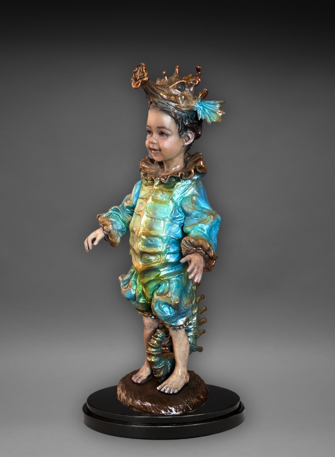 A statue of a young child with a mermaid-like costume, including a crown and fins, on a black base.