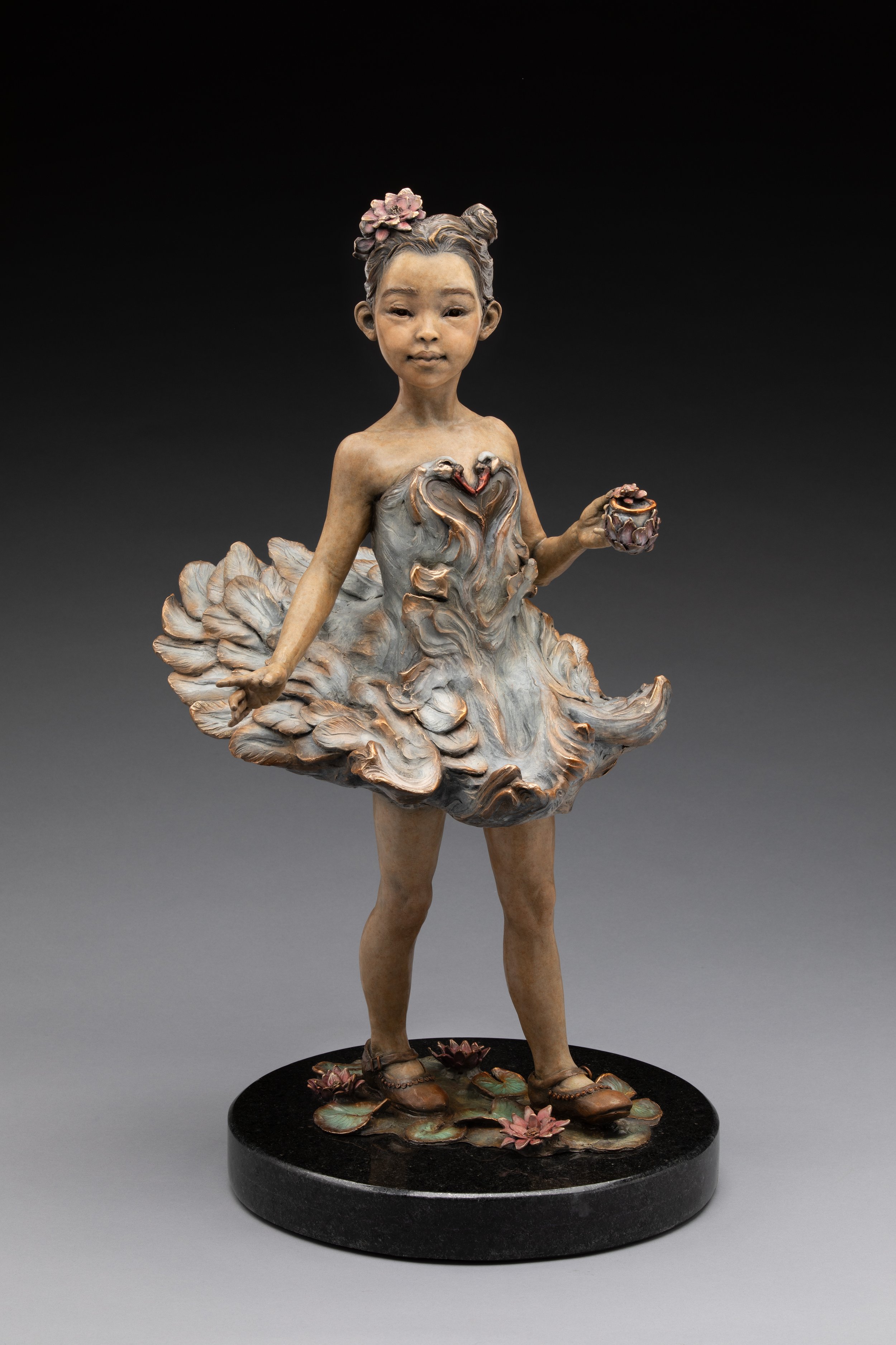 A detailed sculpture of a young girl with a flower in her hair, wearing a dress resembling flower petals, standing on a decorative base with lotus flowers.