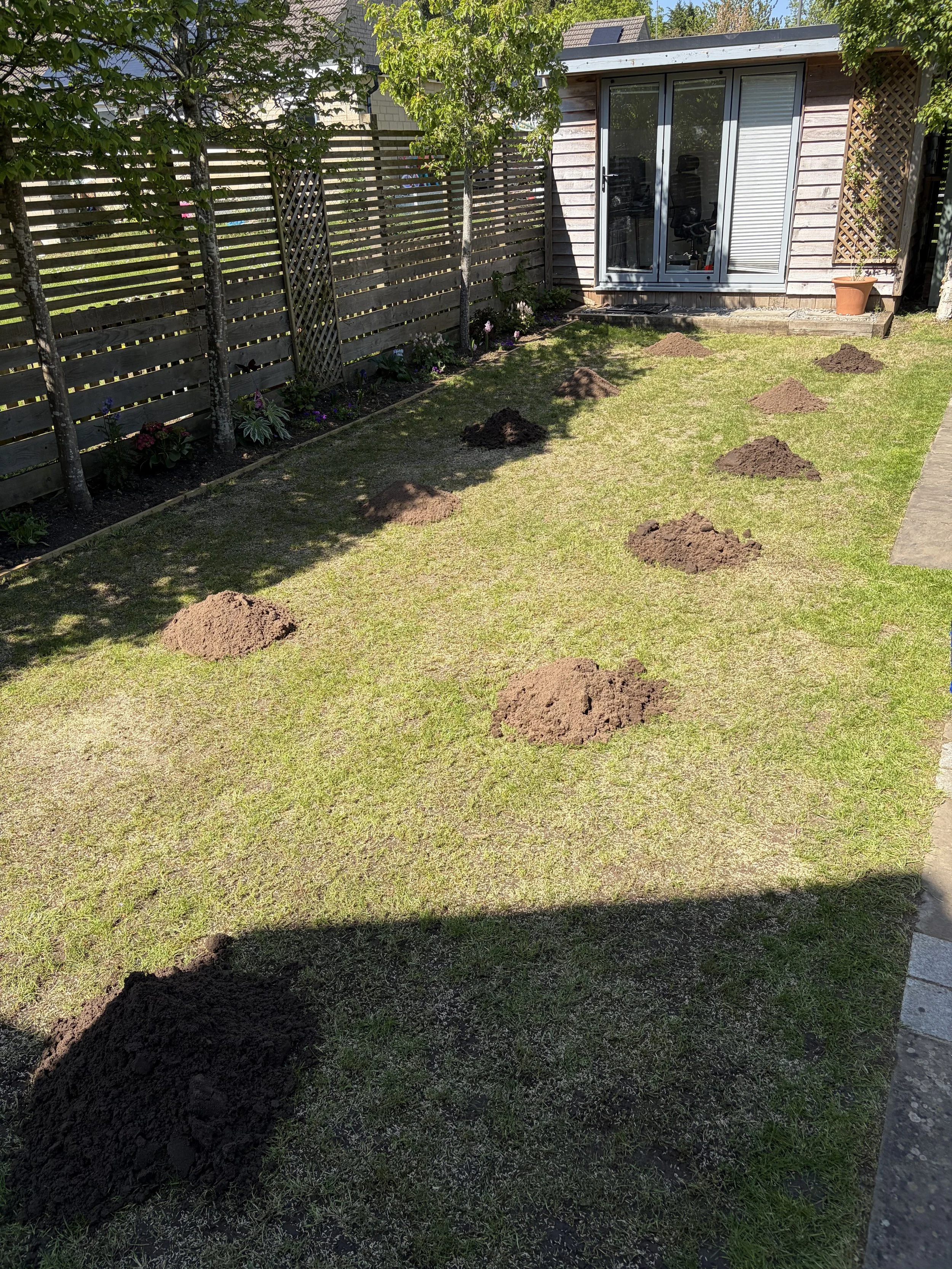 Lawn renovation in Stroud, Gloucestershire, with top dressing soil spread over a newly seeded lawn to improve seed-to-soil contact and encourage even, healthy grass growth.