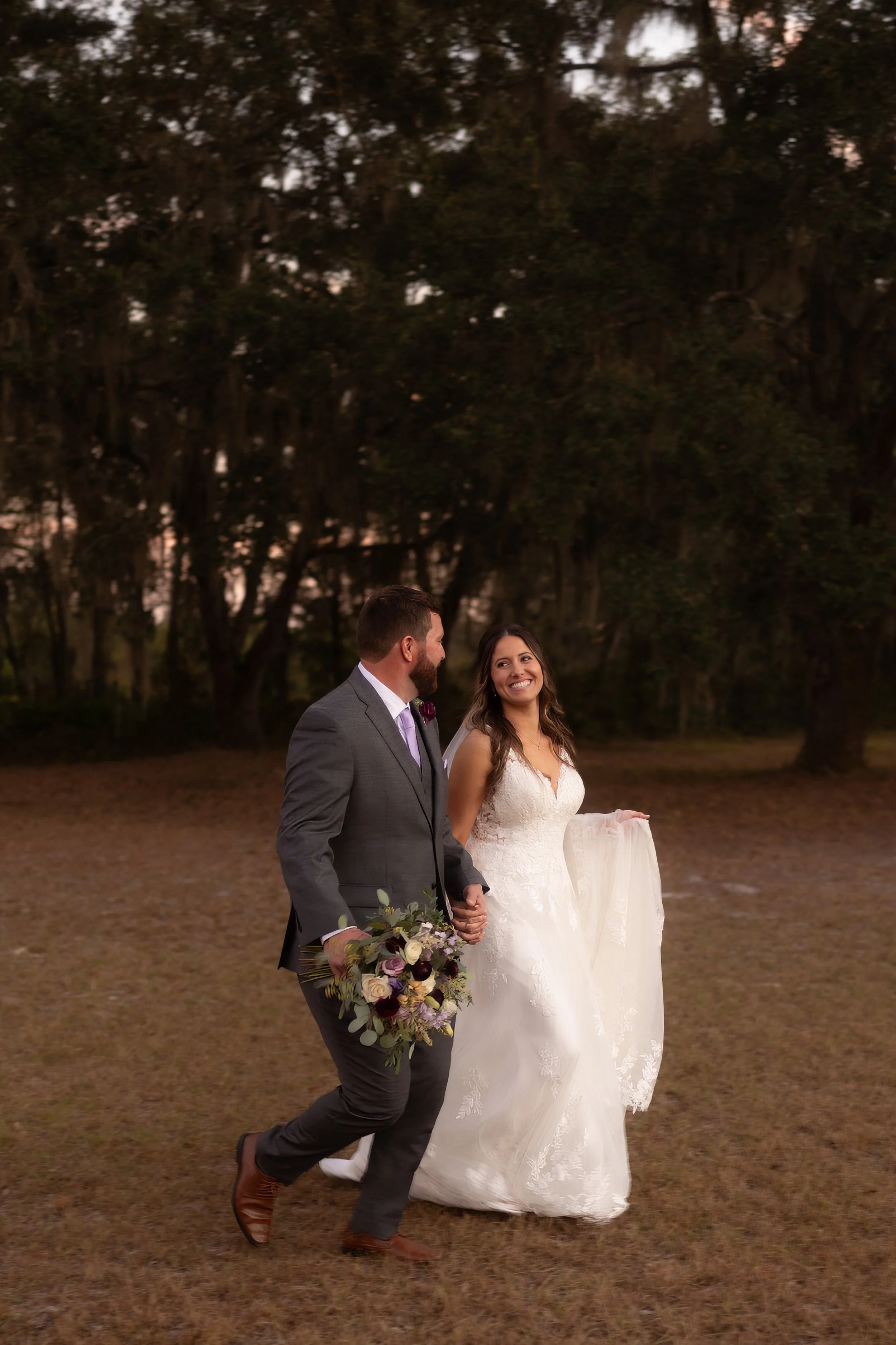 ride and groom walking hand in hand across the field, smiling at each other after their wedding ceremony.