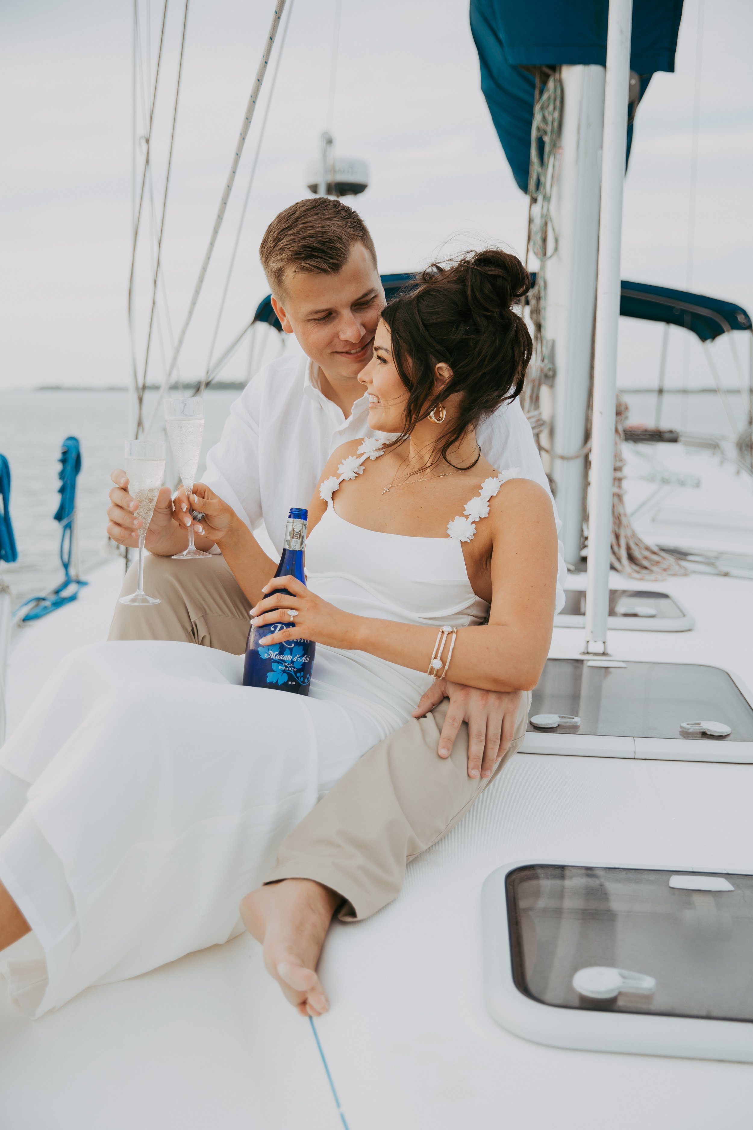 Engaged couple relaxes with a celebratory bottle during their sailing session