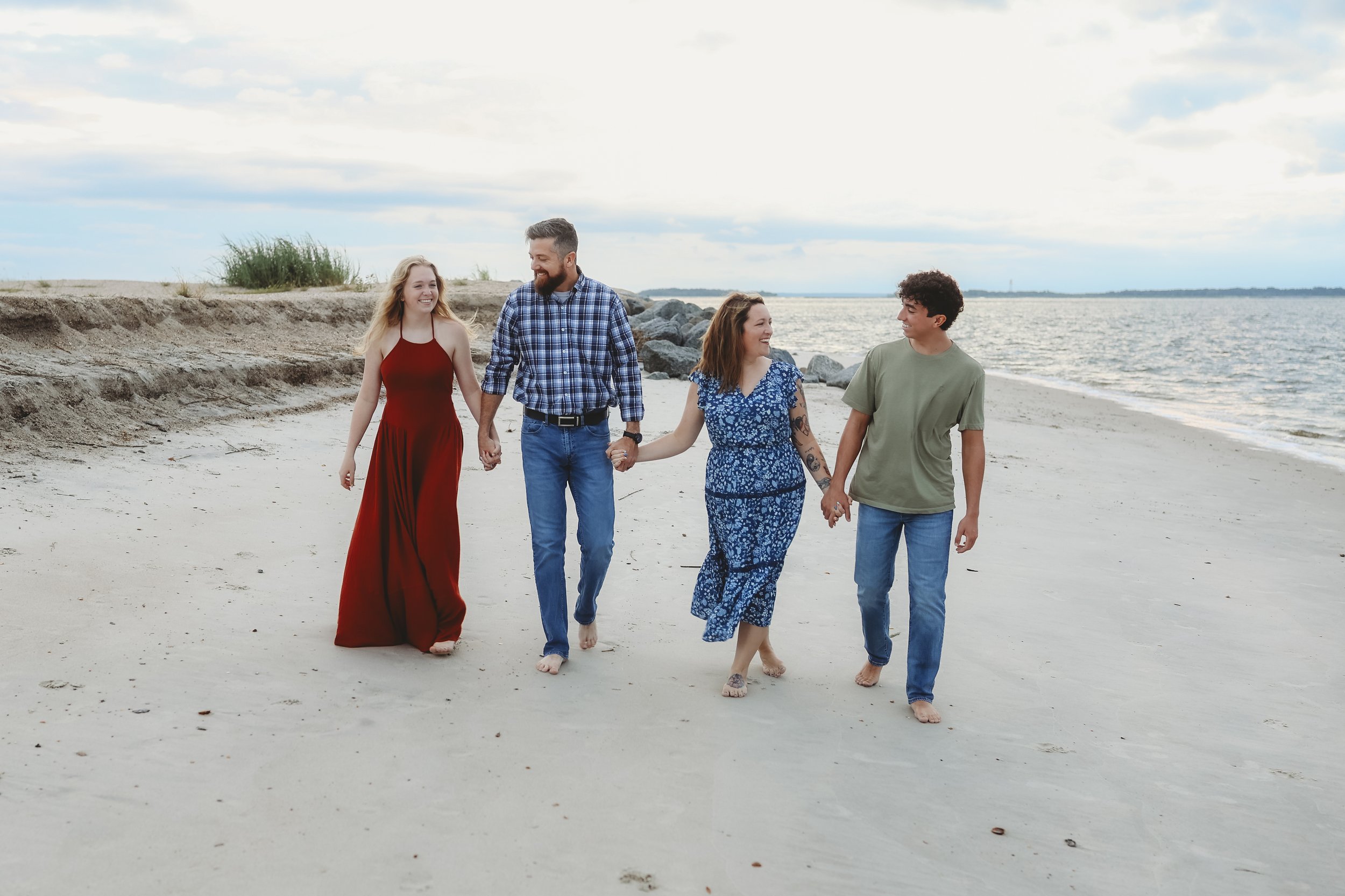 A family gathers on the shoreline rocks, taking in the peaceful sunset together.