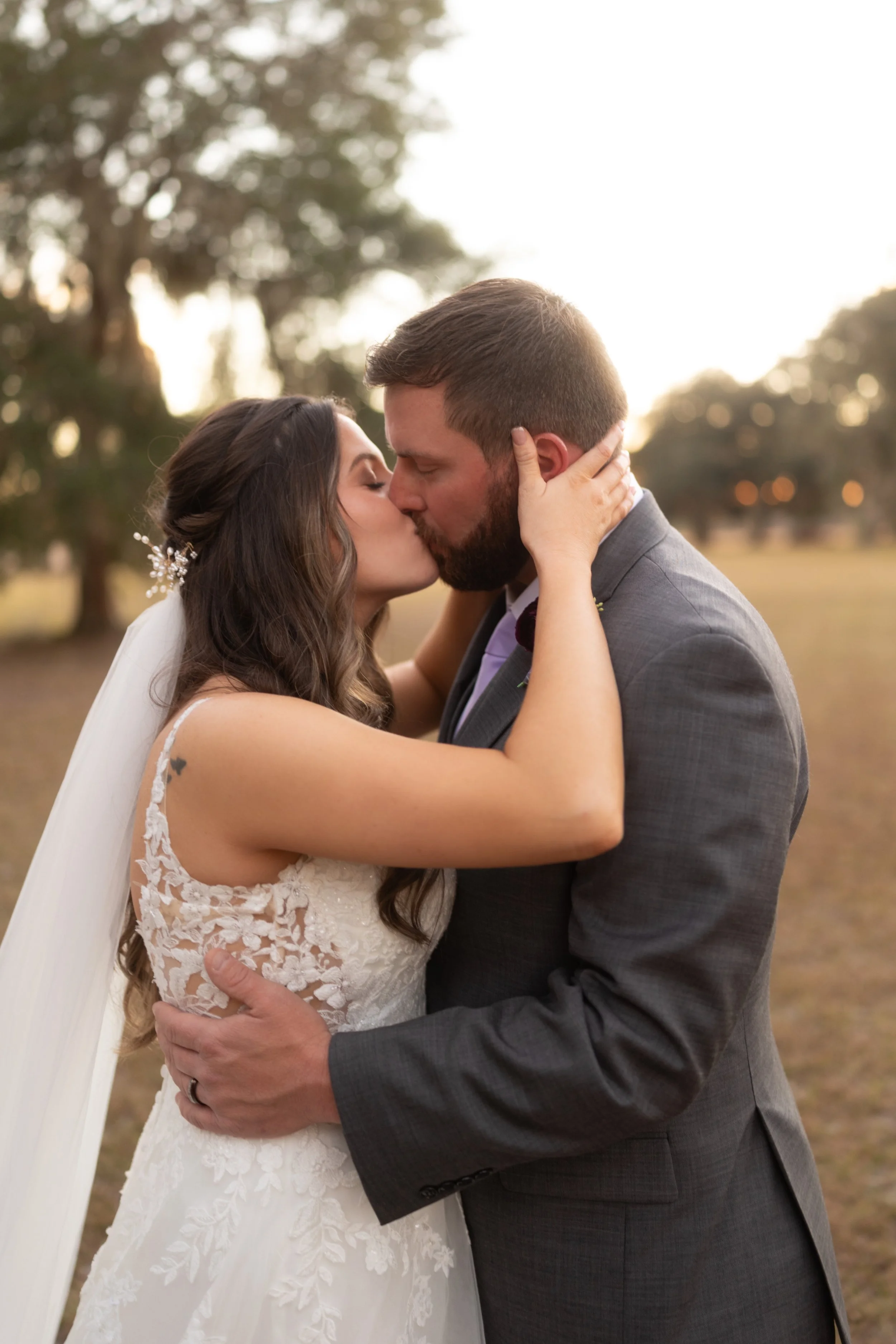 Bride and groom sharing a quiet kiss during golden hour, wrapped in an intimate embrace