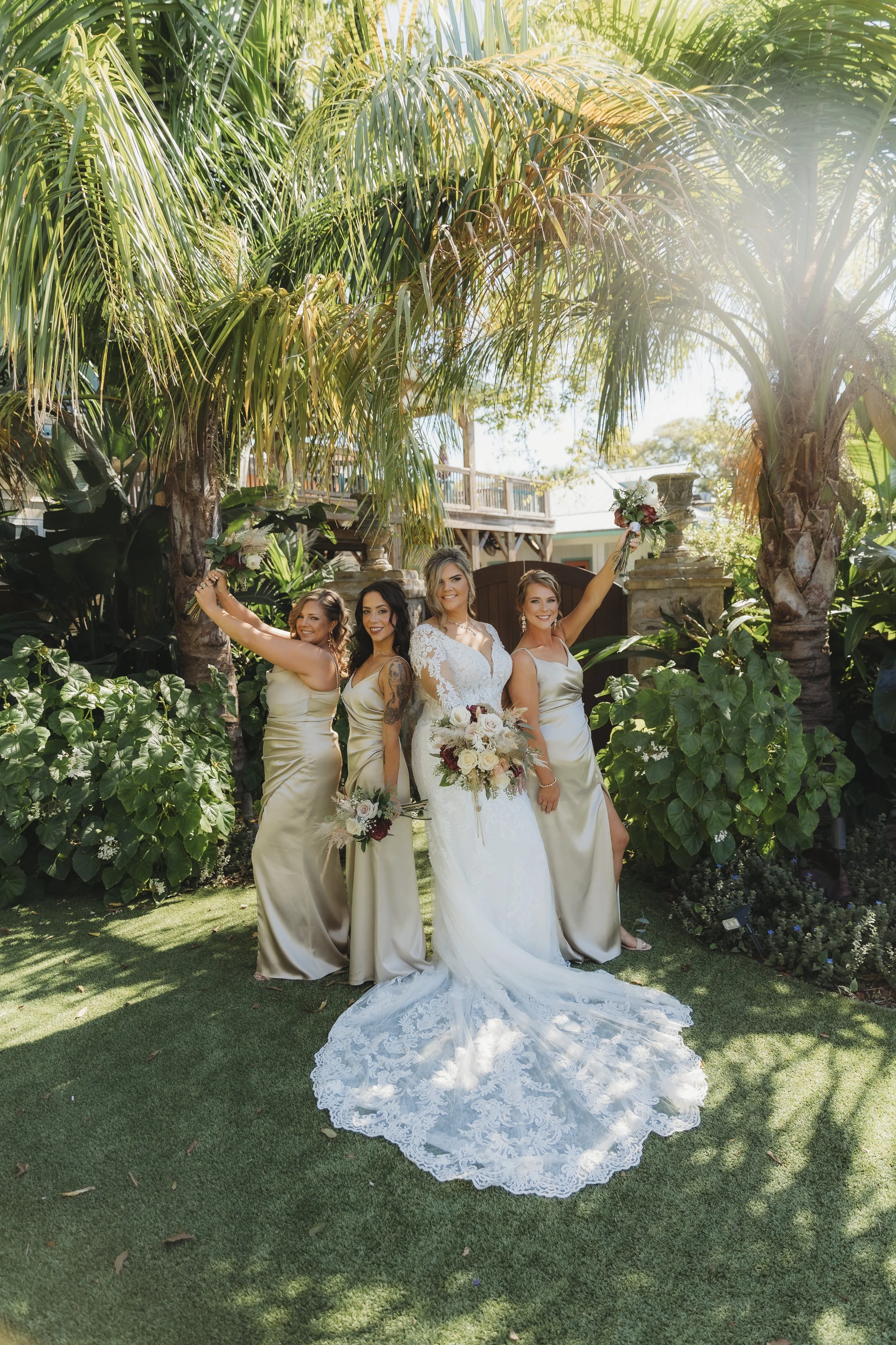 Bride posing with her bridesmaids in matching dresses, celebrating together in a garden setting.