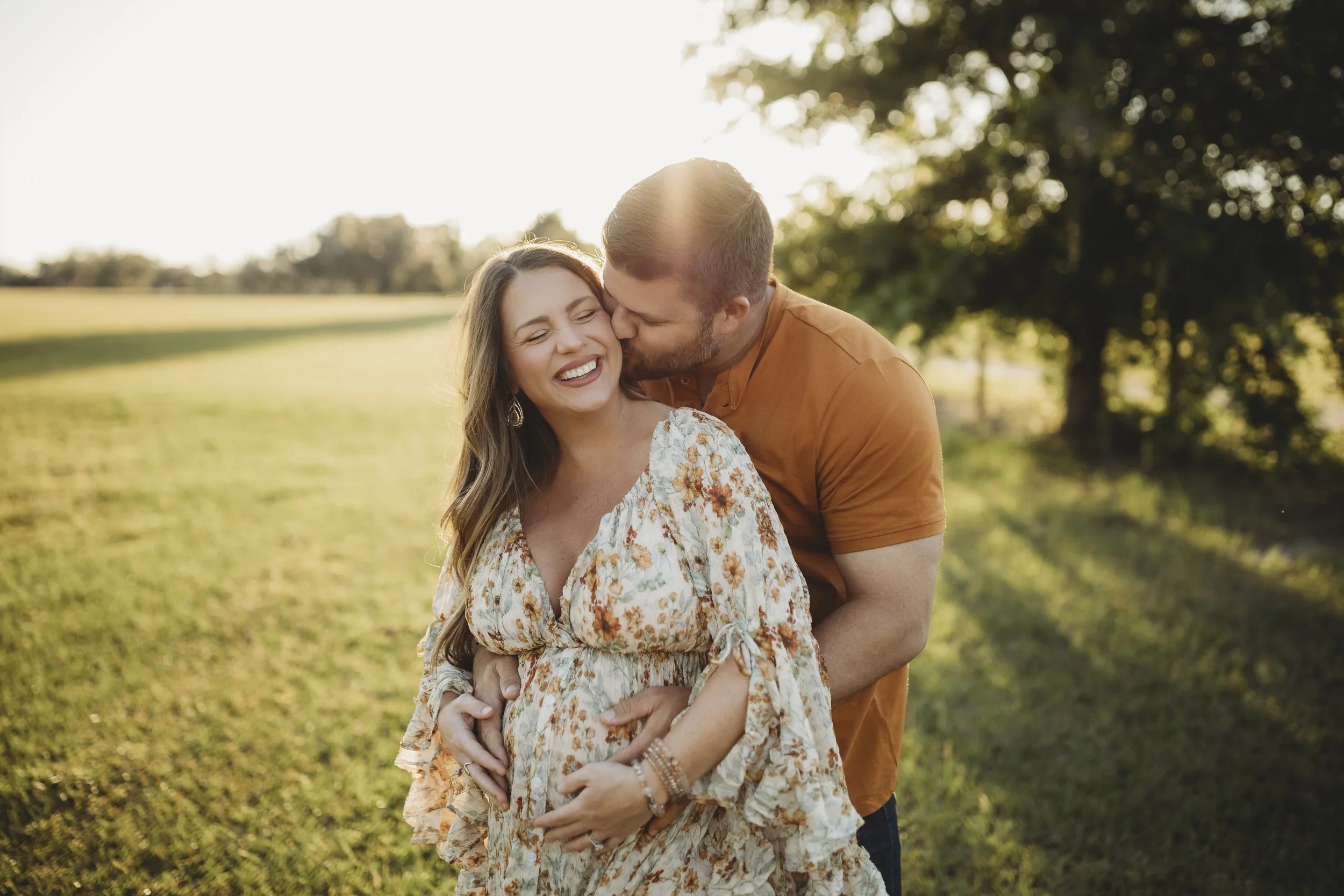Expectant mother laughing as her partner kisses her cheek during a golden-hour maternity photography session in Northeast Florida