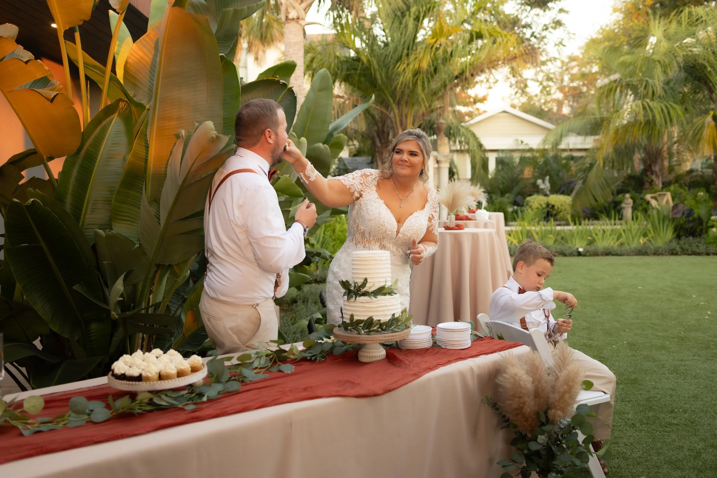 Playful cake-cutting moment between bride and groom outdoors