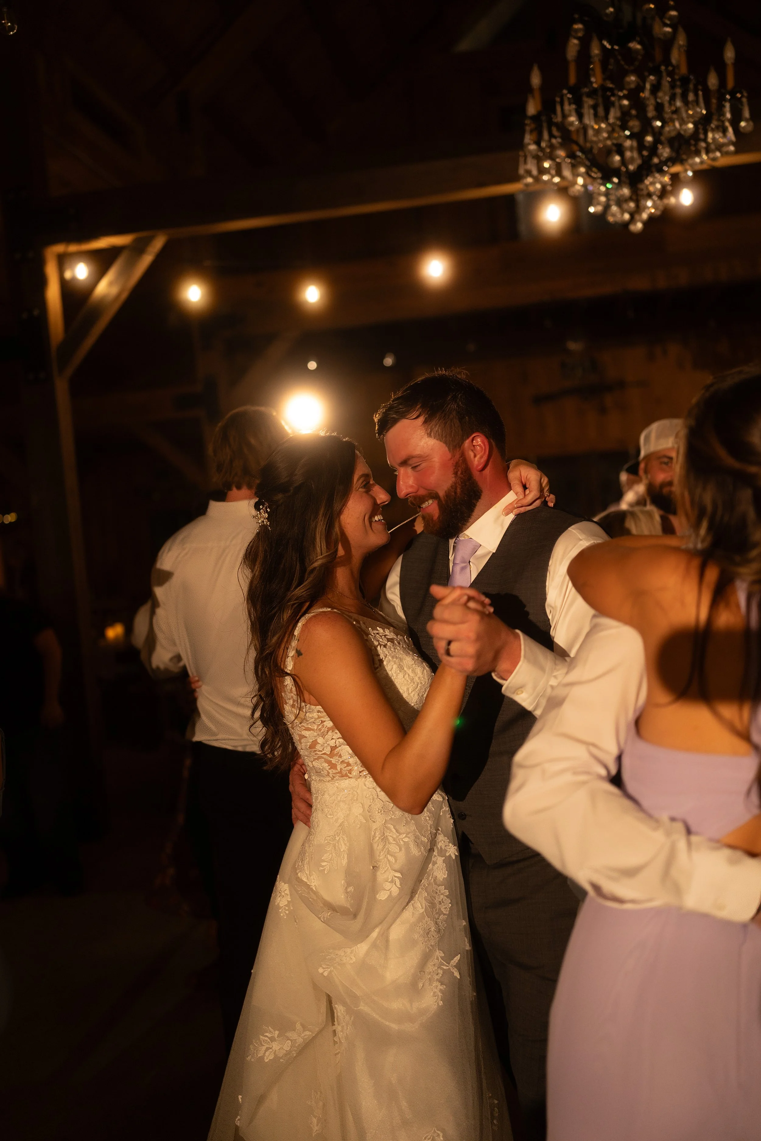 Bride and groom dancing closely together during the wedding reception beneath soft string lights.