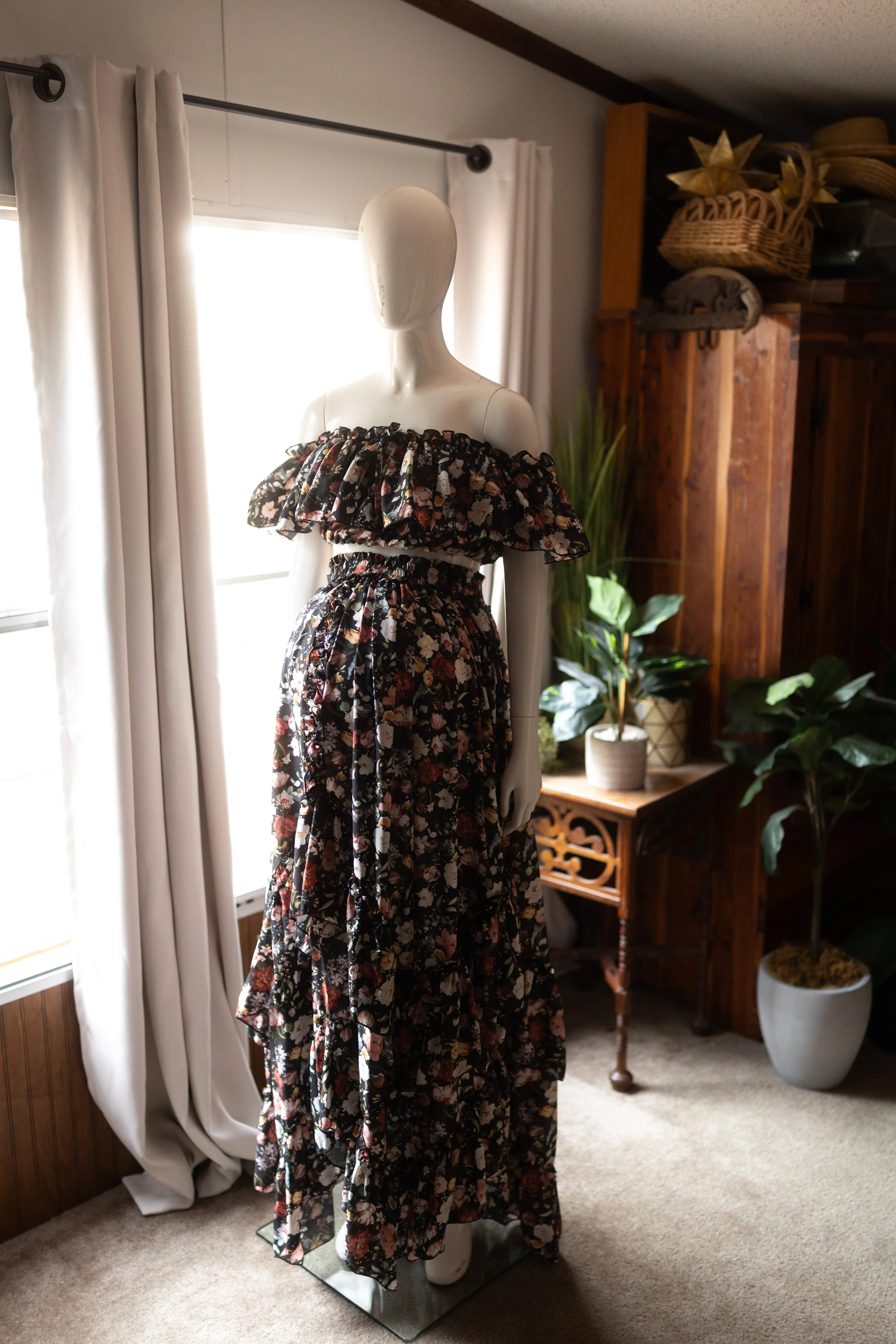 Close-up of dark floral off-the-shoulder maternity dress with ruffled neckline and gathered waist, styled above the belly.