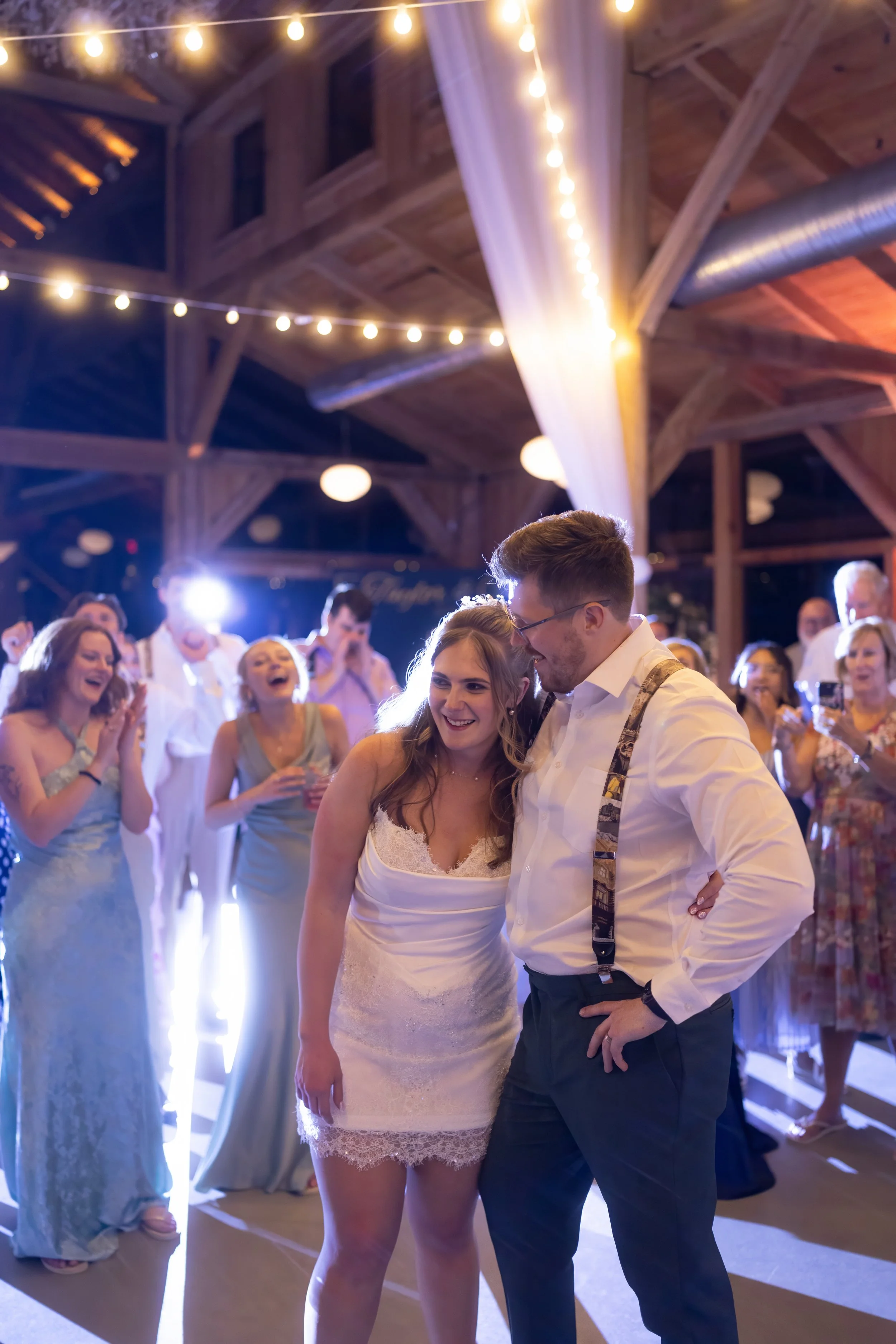 Newlyweds smile together as friends and family cheer them on during the wedding reception at Cottonwood Ranch.