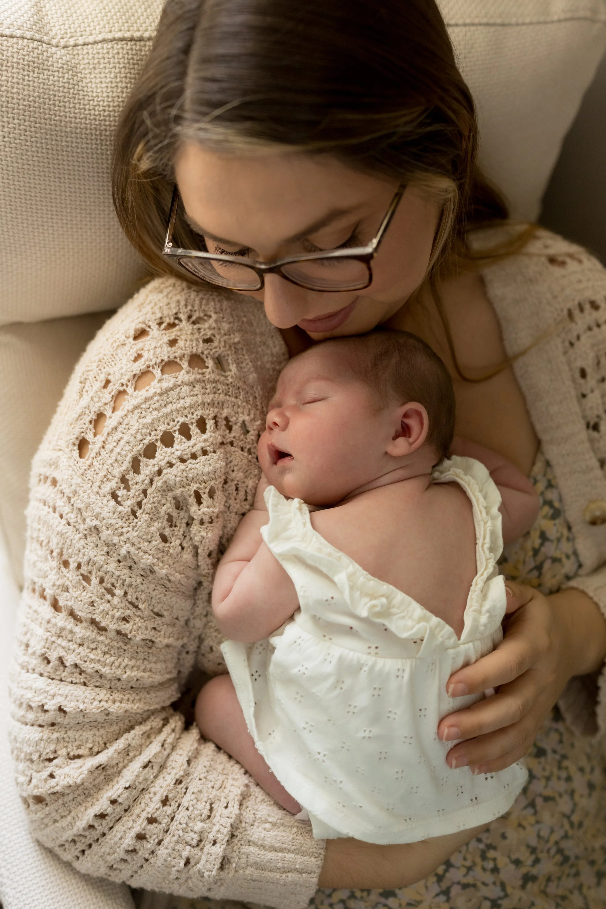 Mother kissing her newborn baby while cuddling together during a natural in-home newborn photography session in Northeast Florida.