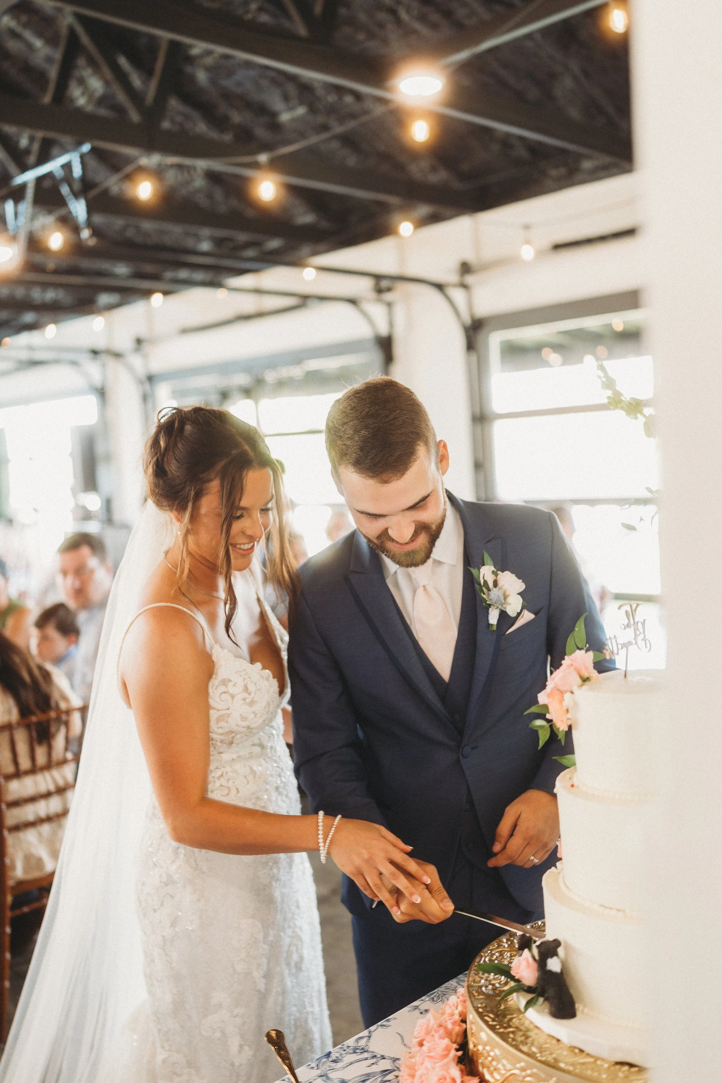 Emmie and Dylan smile as they cut their white wedding cake during their reception at Red River Estate.