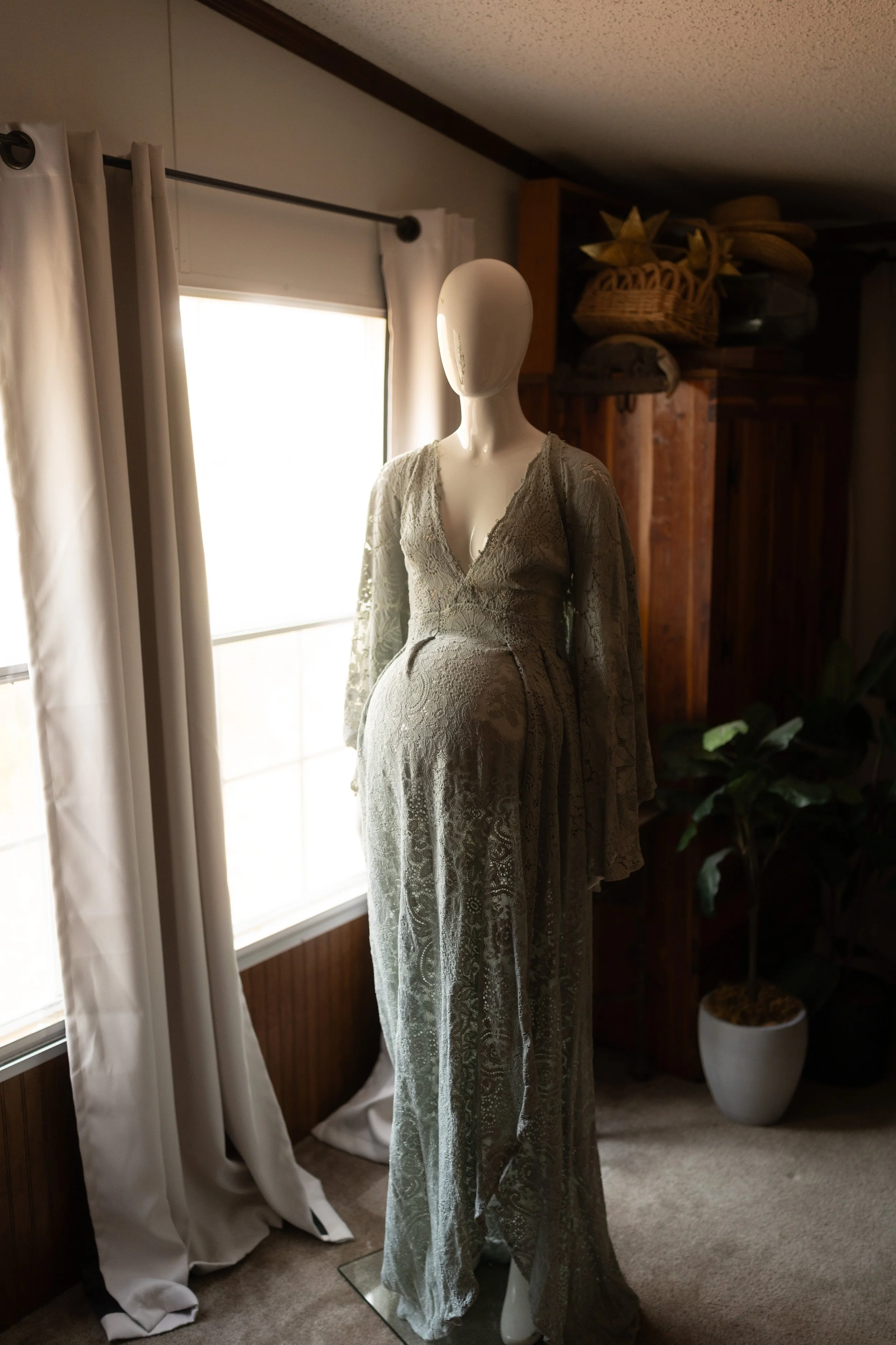 Soft lace maxi dress with long sleeves, a deep V neckline, and an intricate floral lace pattern, styled on a mannequin in warm natural light.