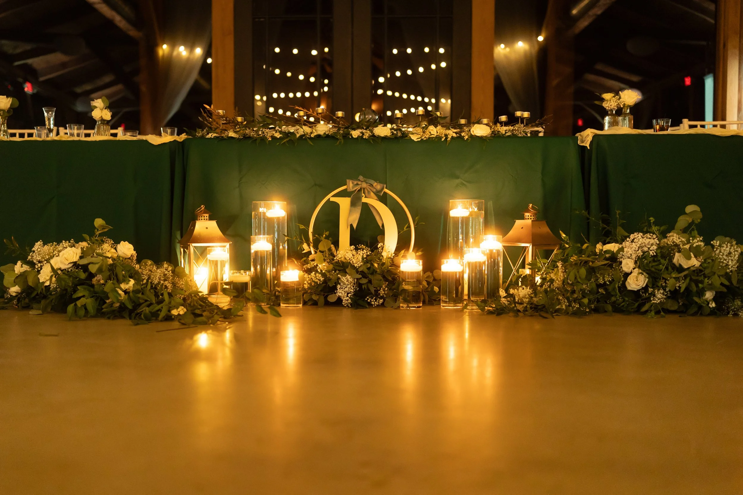 Candlelit greenery decor adorns the sweetheart table during the evening reception.
