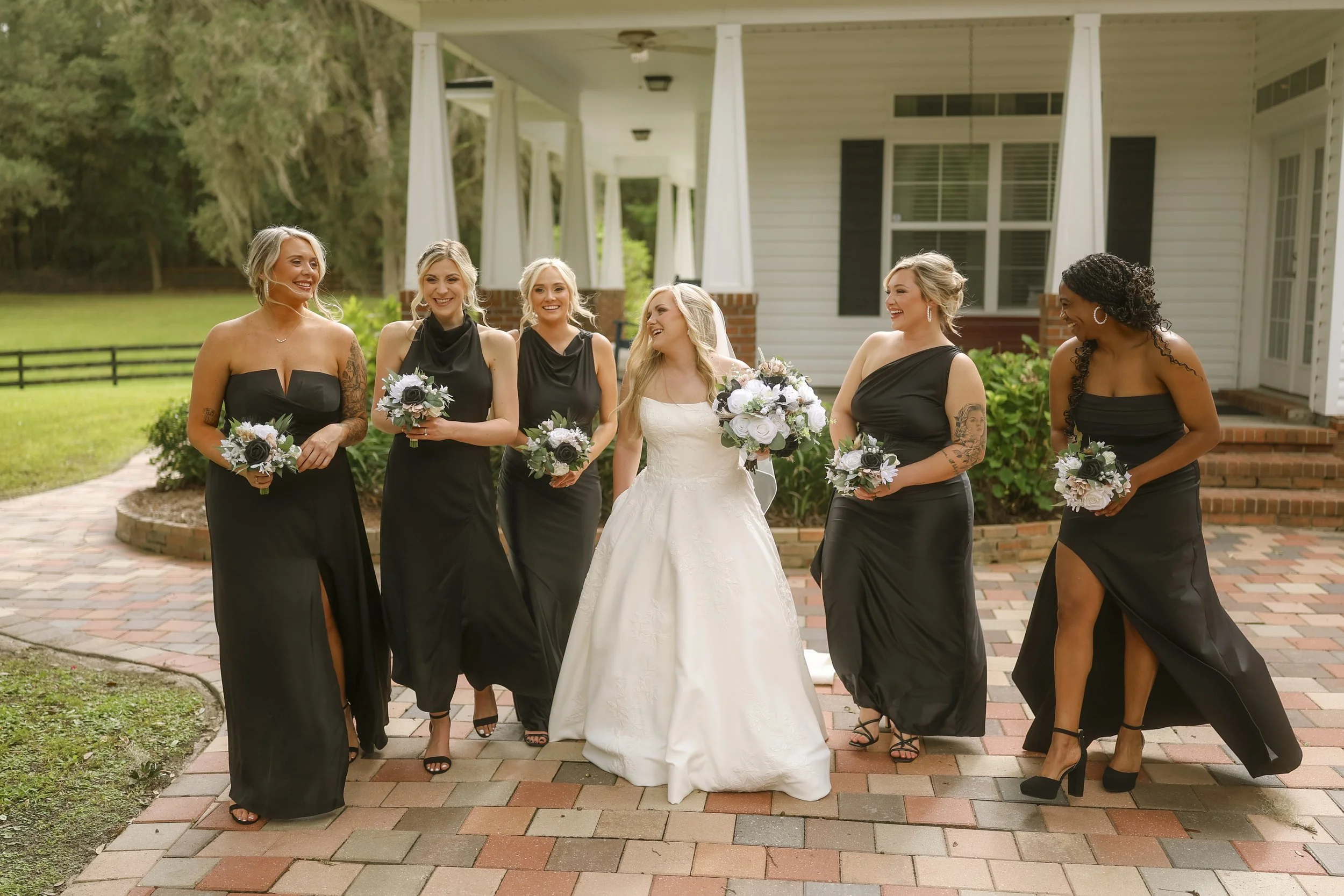 A joyful walk with bridesmaids dressed in black, bouquets in hand, capturing the ease, trust, and deep friendship that carried her to this day.