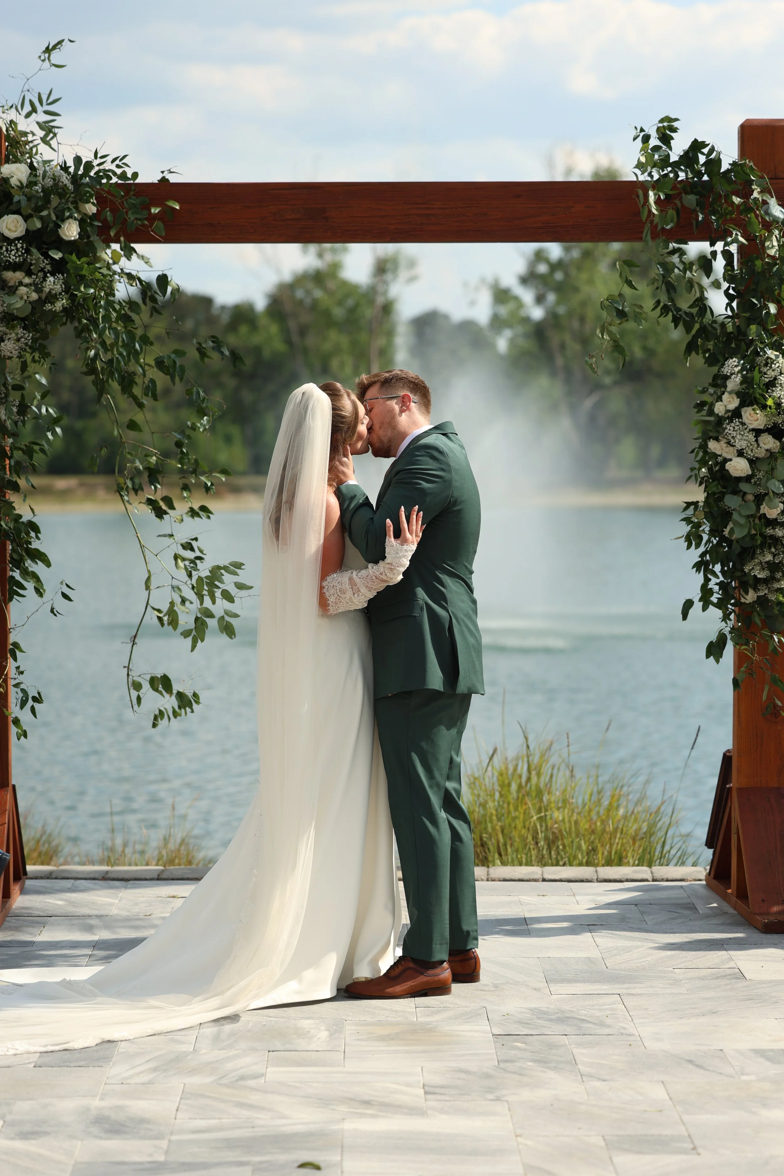 The groom leans against a wooden post for a relaxed portrait before the ceremony.