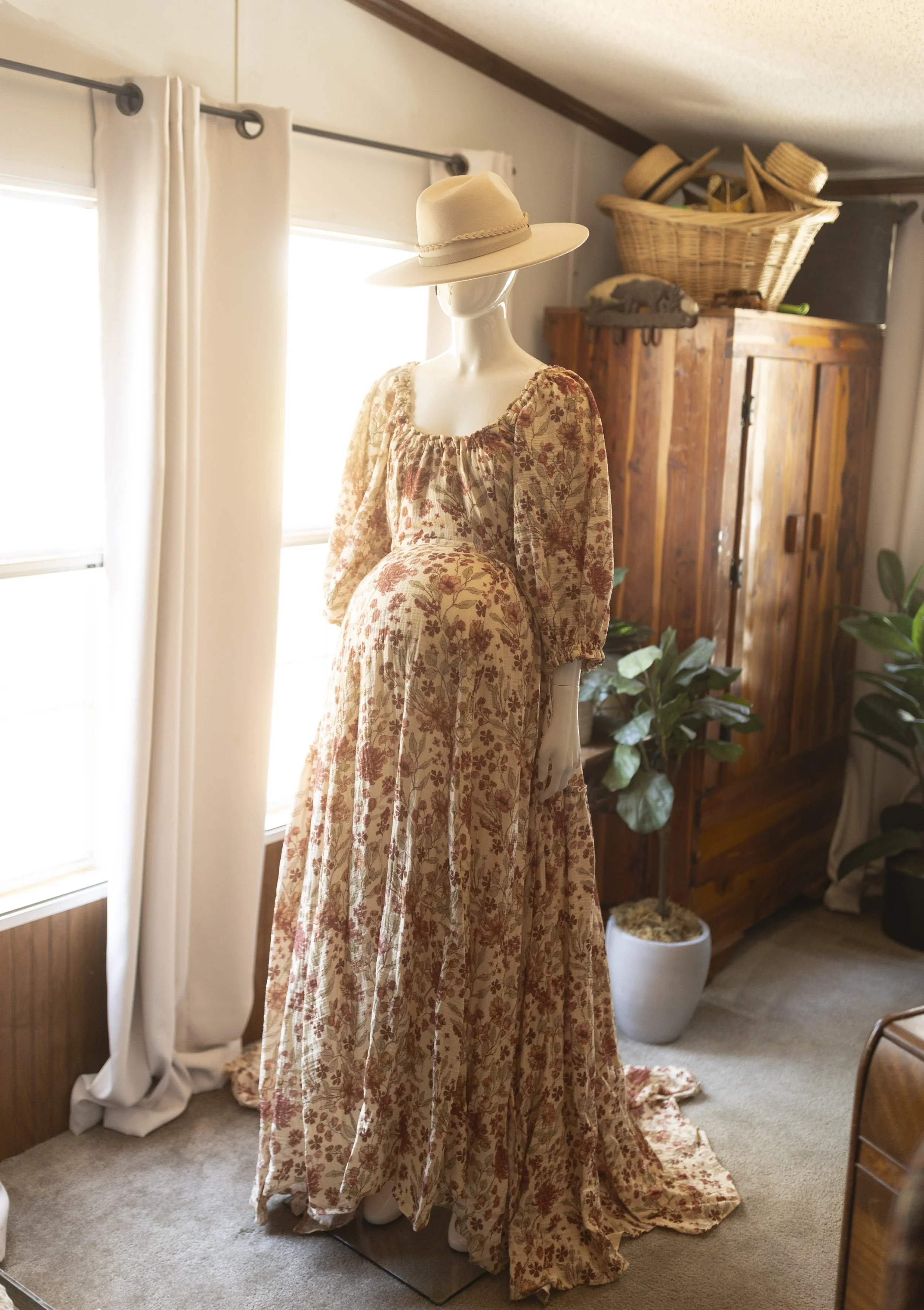 Flowy boho maxi dress with a soft floral pattern, long puff sleeves, and a gathered neckline, styled on a mannequin in warm natural light for a romantic, whimsical look.