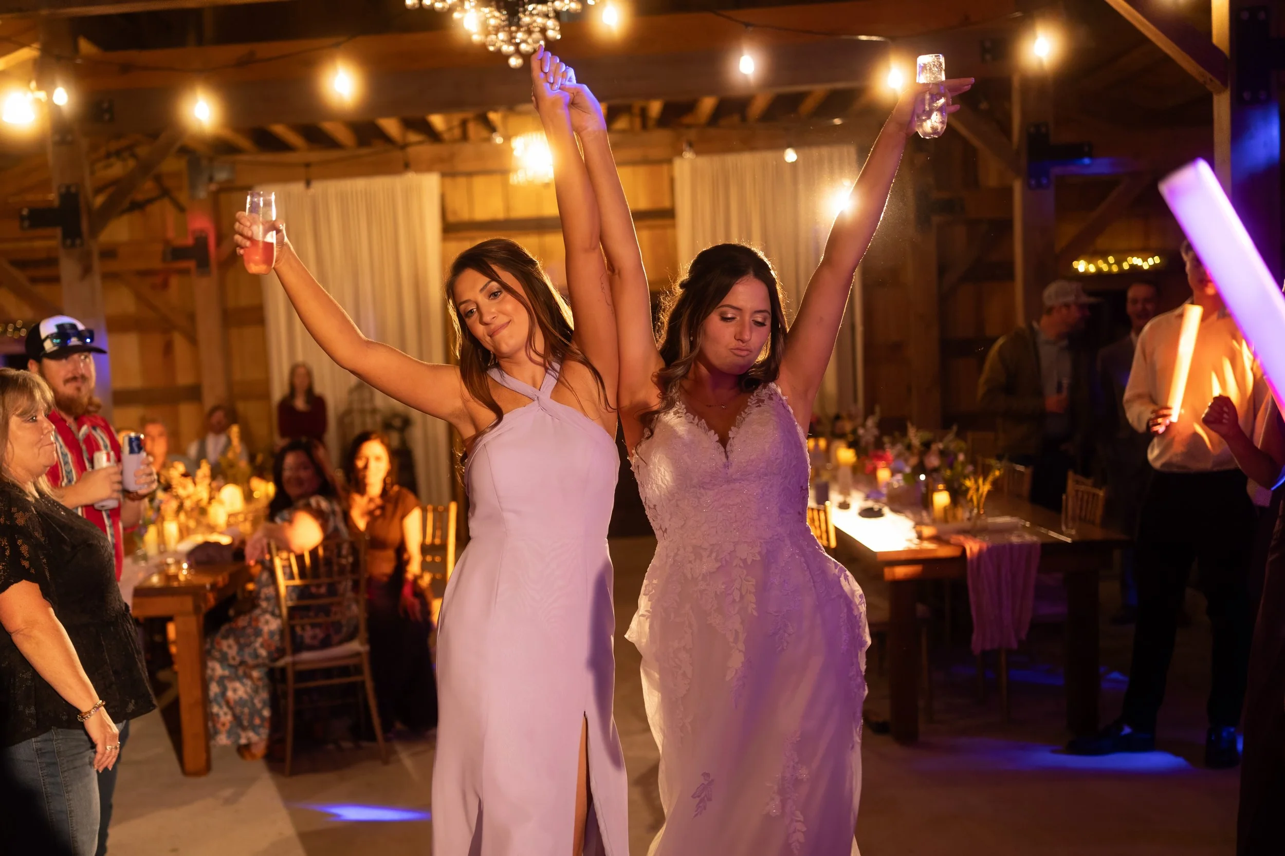 Bride and her sister dancing together with their hands raised during the wedding reception.