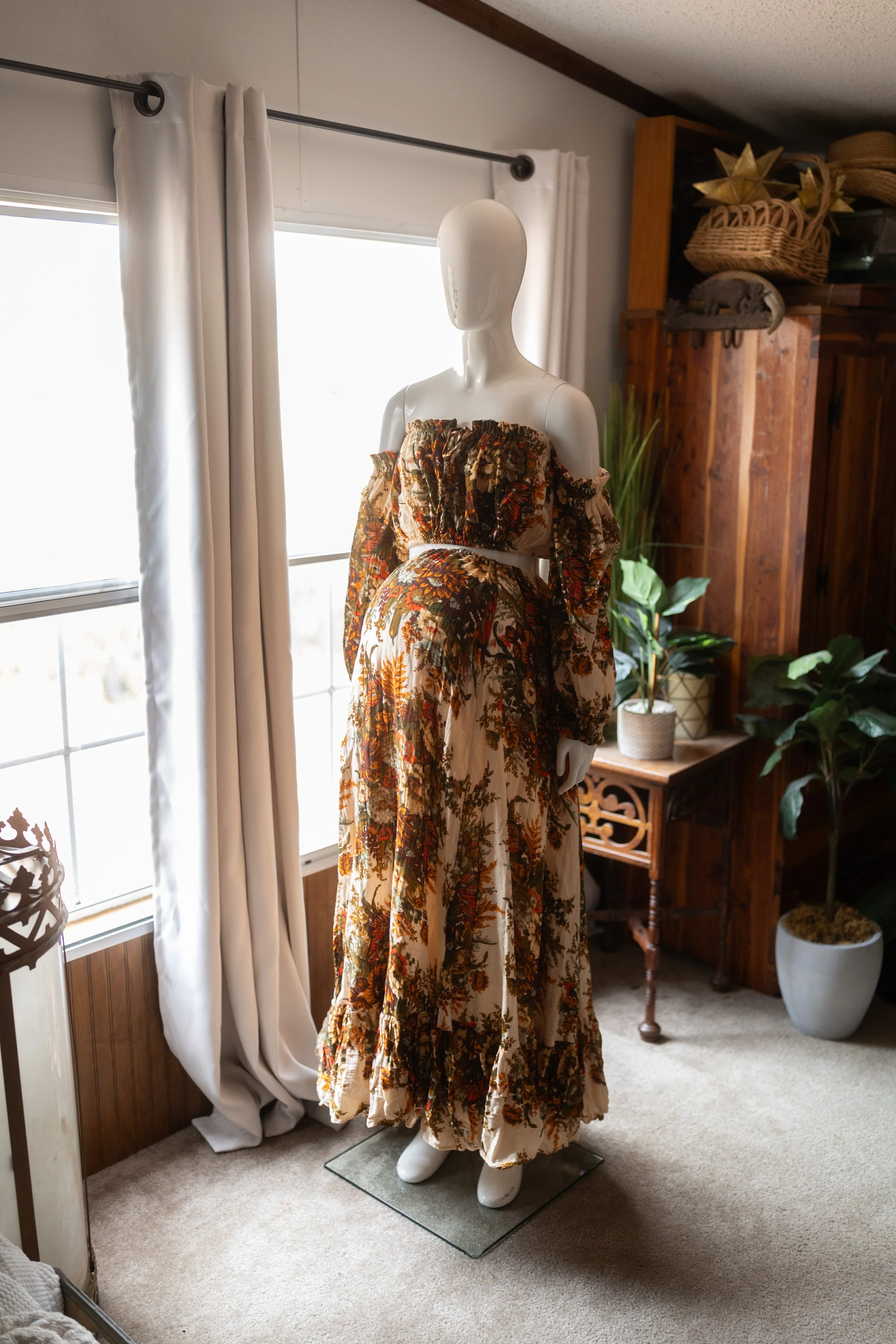 70’s-inspired floral maternity dress styled over the baby bump, featuring an off-the-shoulder neckline and bold earthy tones.