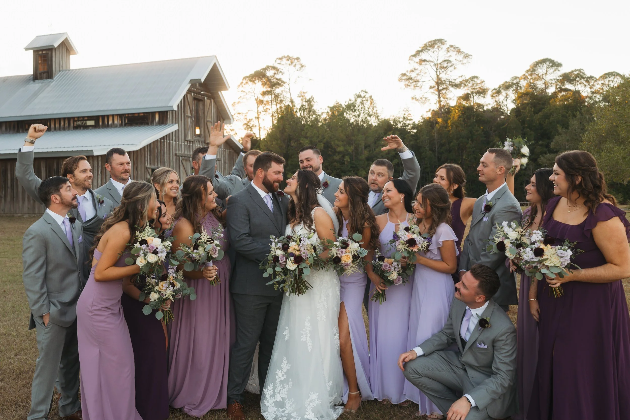 Bride and groom sharing a joyful moment as their wedding party cheers around them on their wedding day.