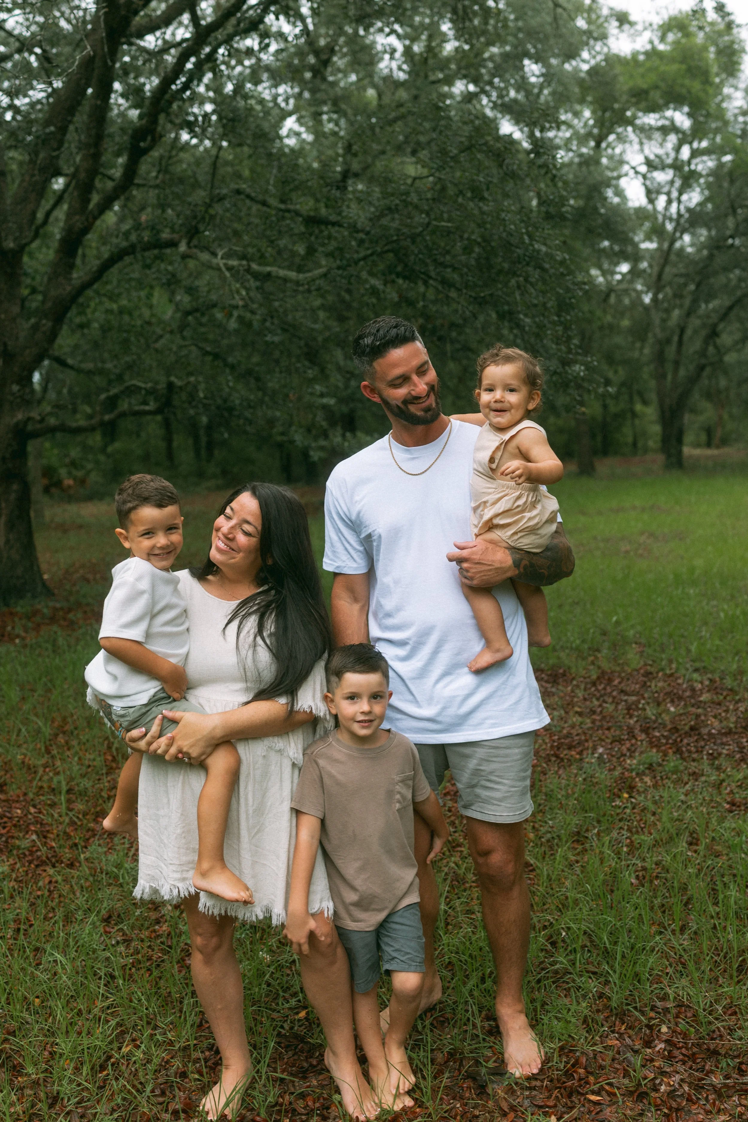 Family of five smiling together in a wooded field during a relaxed outdoor family photography session in Northeast Florida