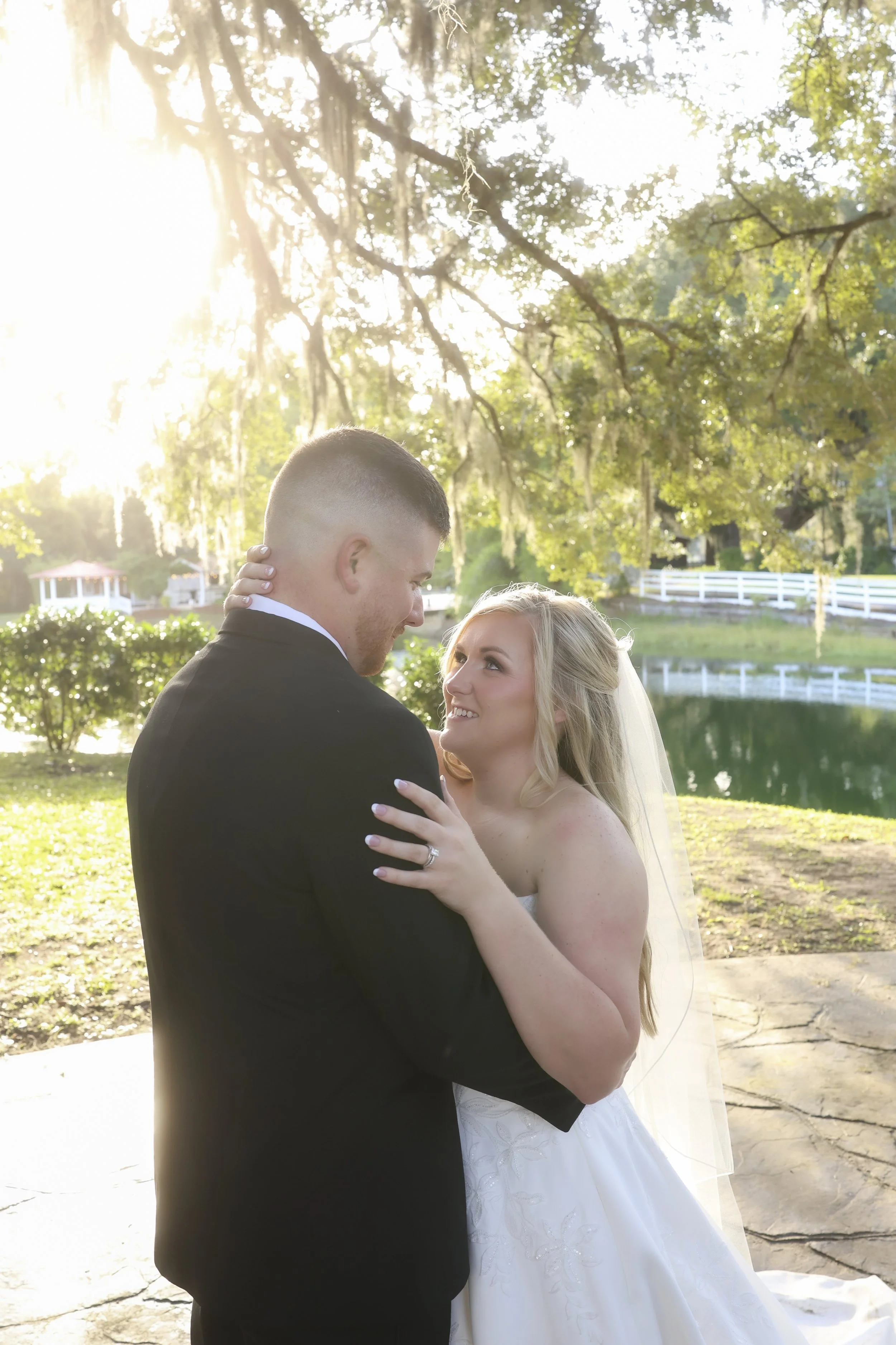 Wrapped in golden light, she looks up at him with a quiet smile, the world fading as they hold each other close.