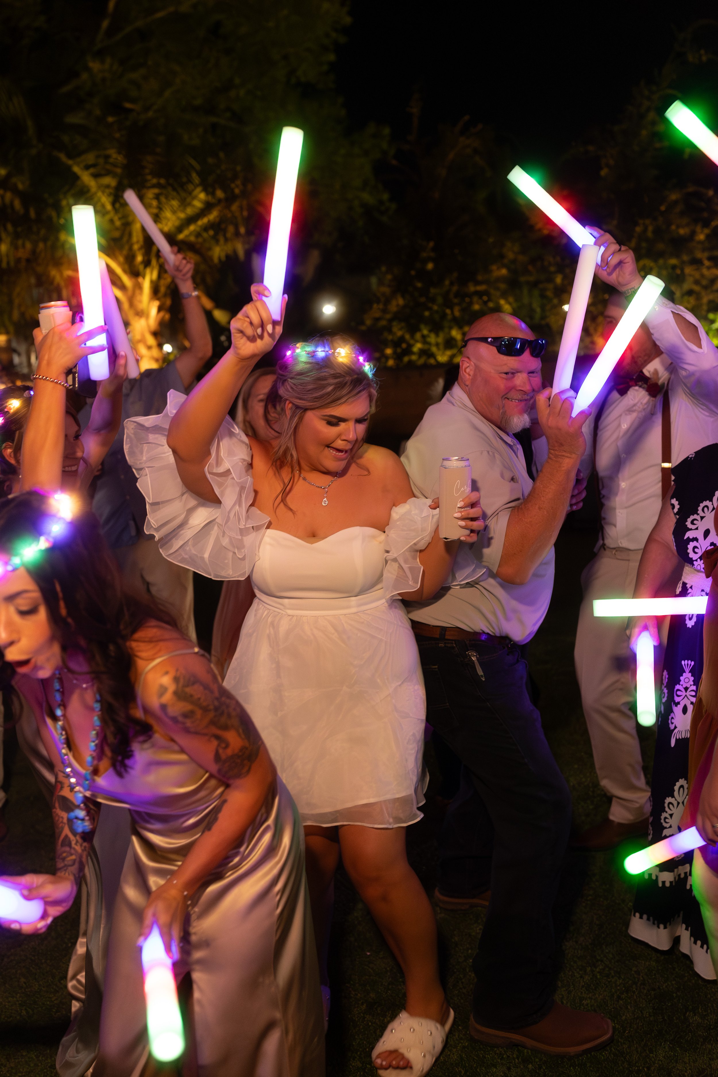 High-energy wedding dance floor with glow sticks and celebration