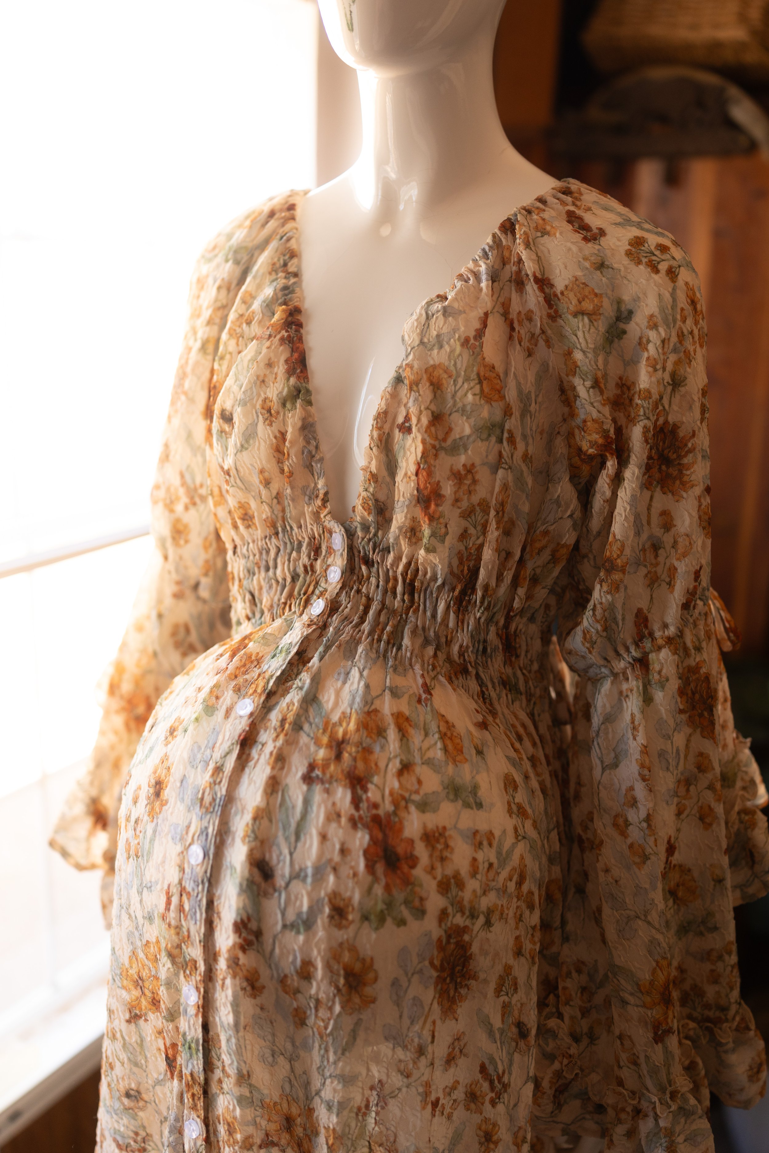 Romantic floral dress detail featuring gentle ruching, warm earthy colors, and an effortlessly feminine feel.