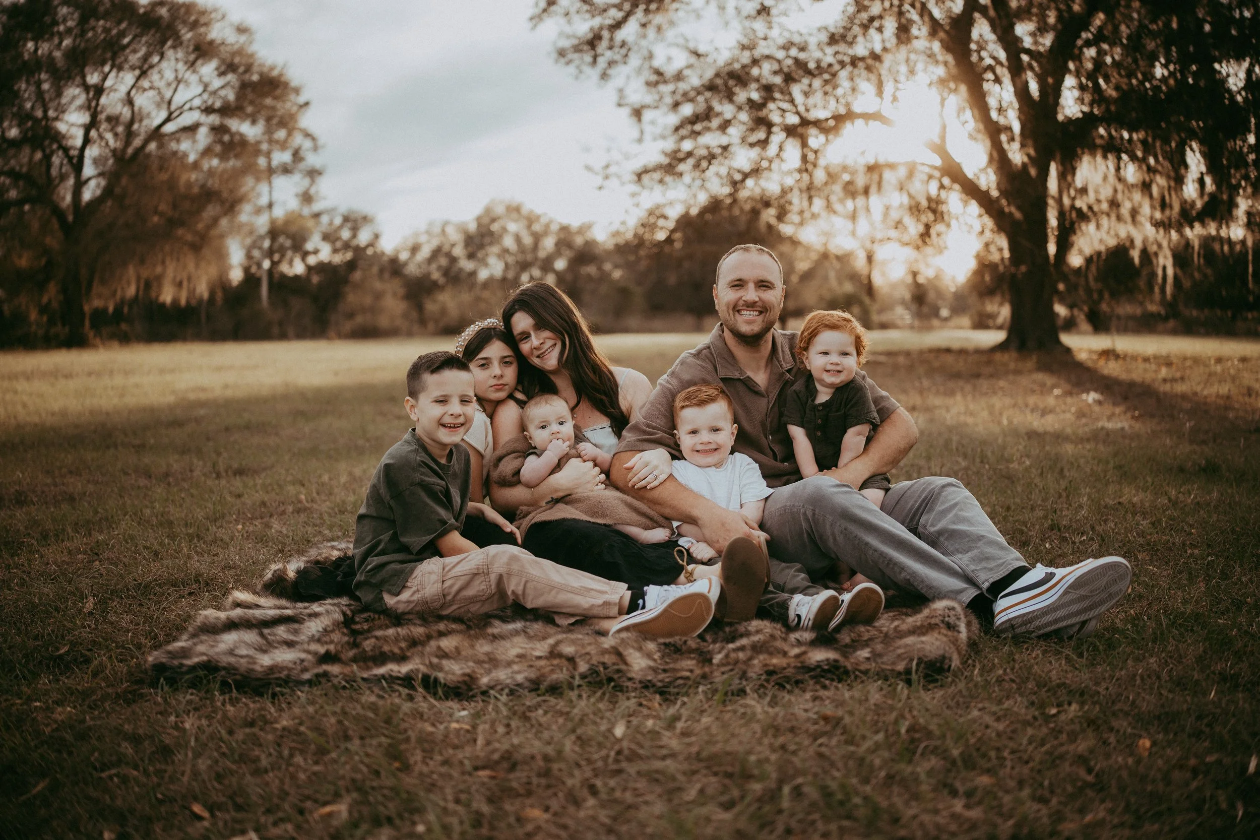 Outdoor family portrait beneath oak trees at sunset, creating timeless wall art that celebrates genuine connection and the love shared between generations.