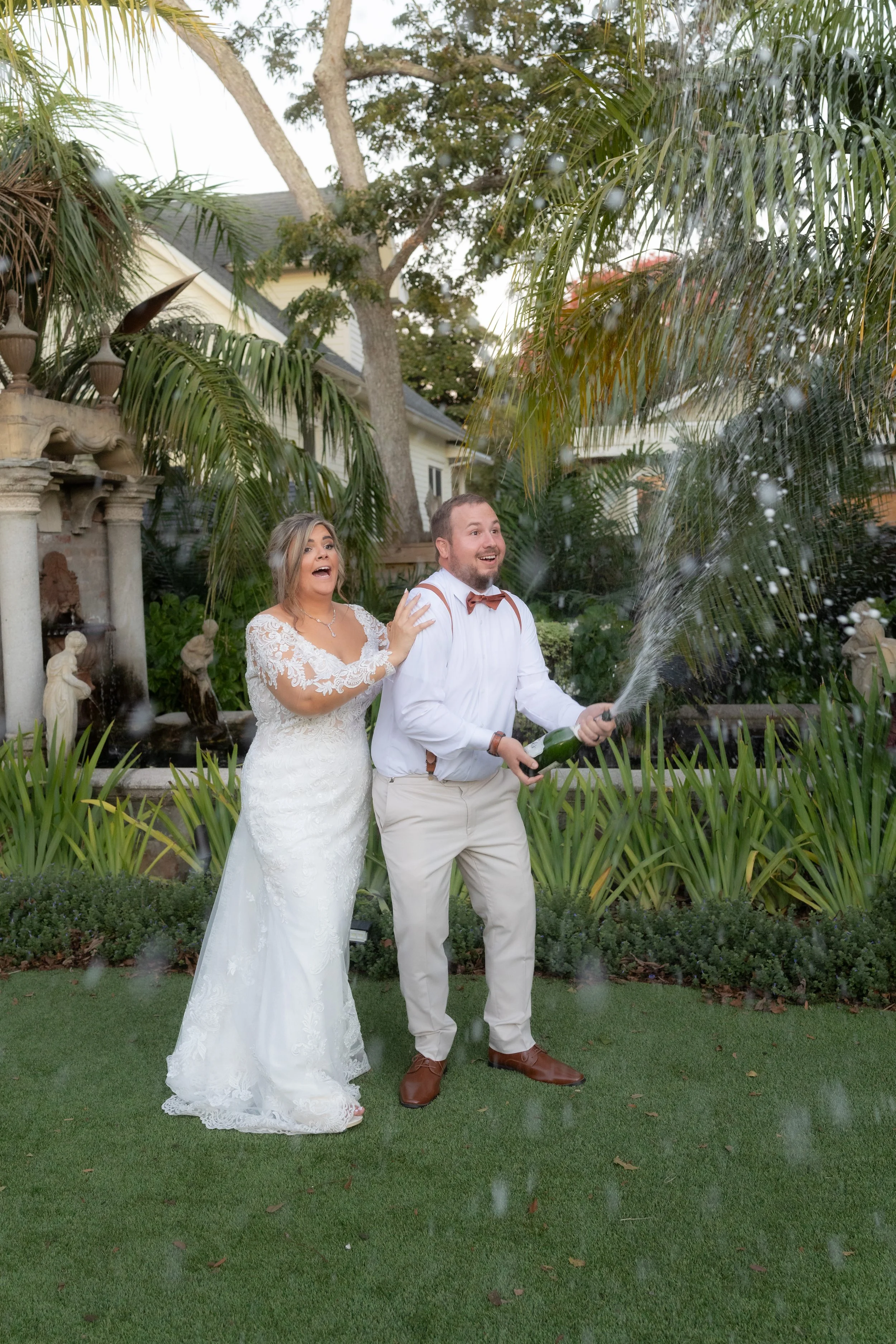 Bride laughing as groom pops champagne at their wedding