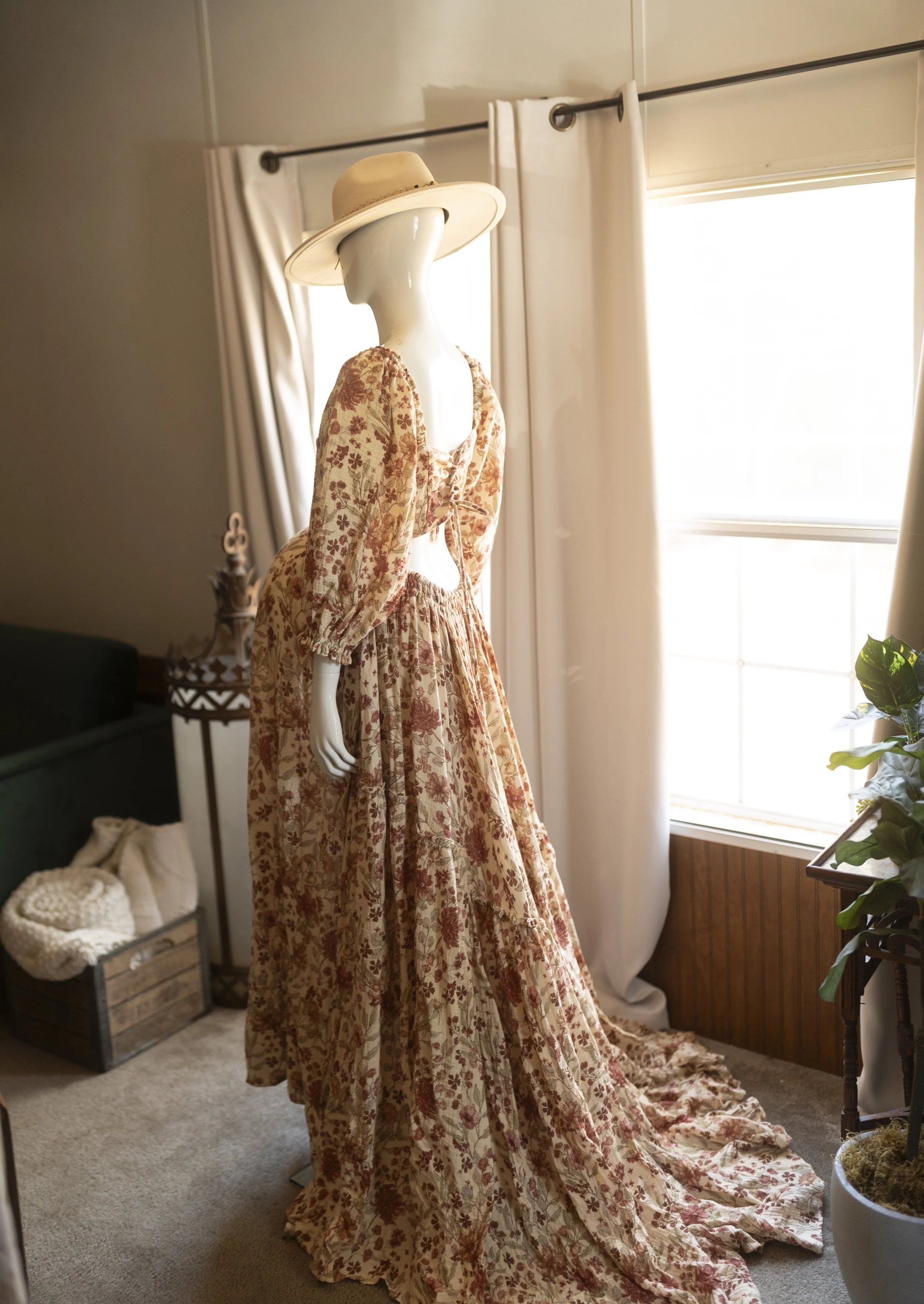 Flowy boho maxi dress with a soft floral pattern, long puff sleeves, and a gathered neckline, styled on a mannequin in warm natural light for a romantic, whimsical look.