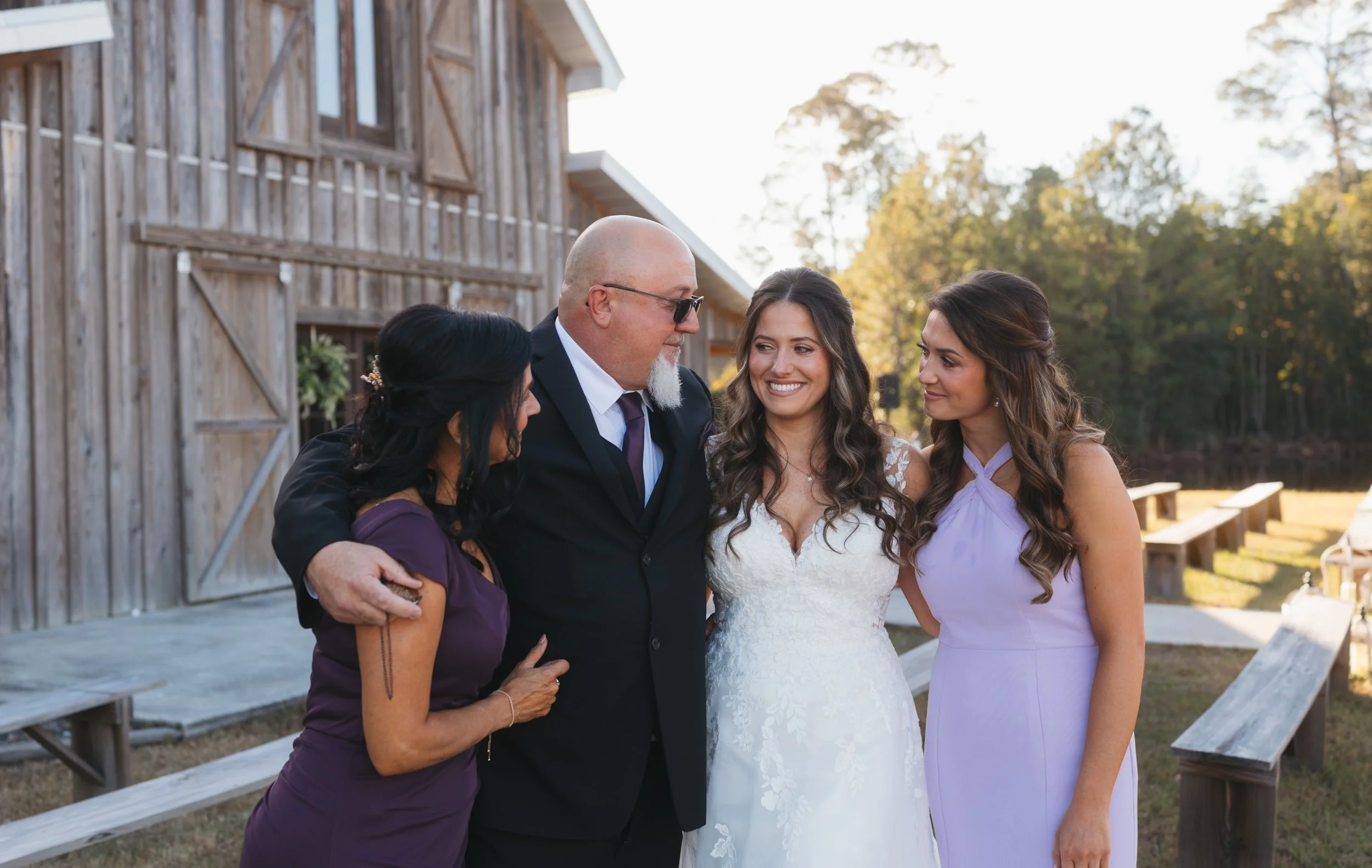 Bride surrounded by her family, smiling together outdoors on her wedding day.