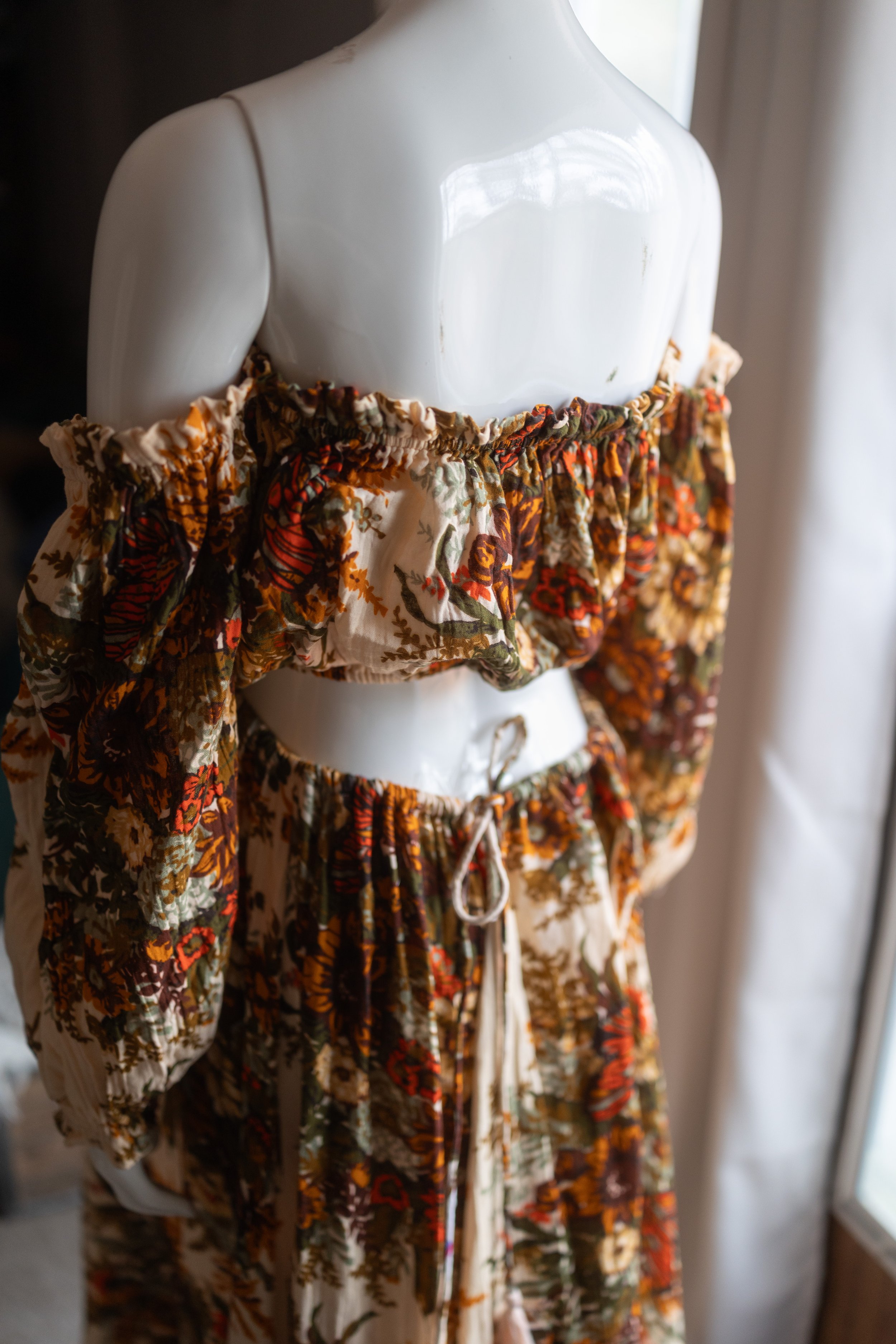 Retro floral maternity dress with gathered off-the-shoulder bodice and rich autumn tones, styled to sit over the bump.