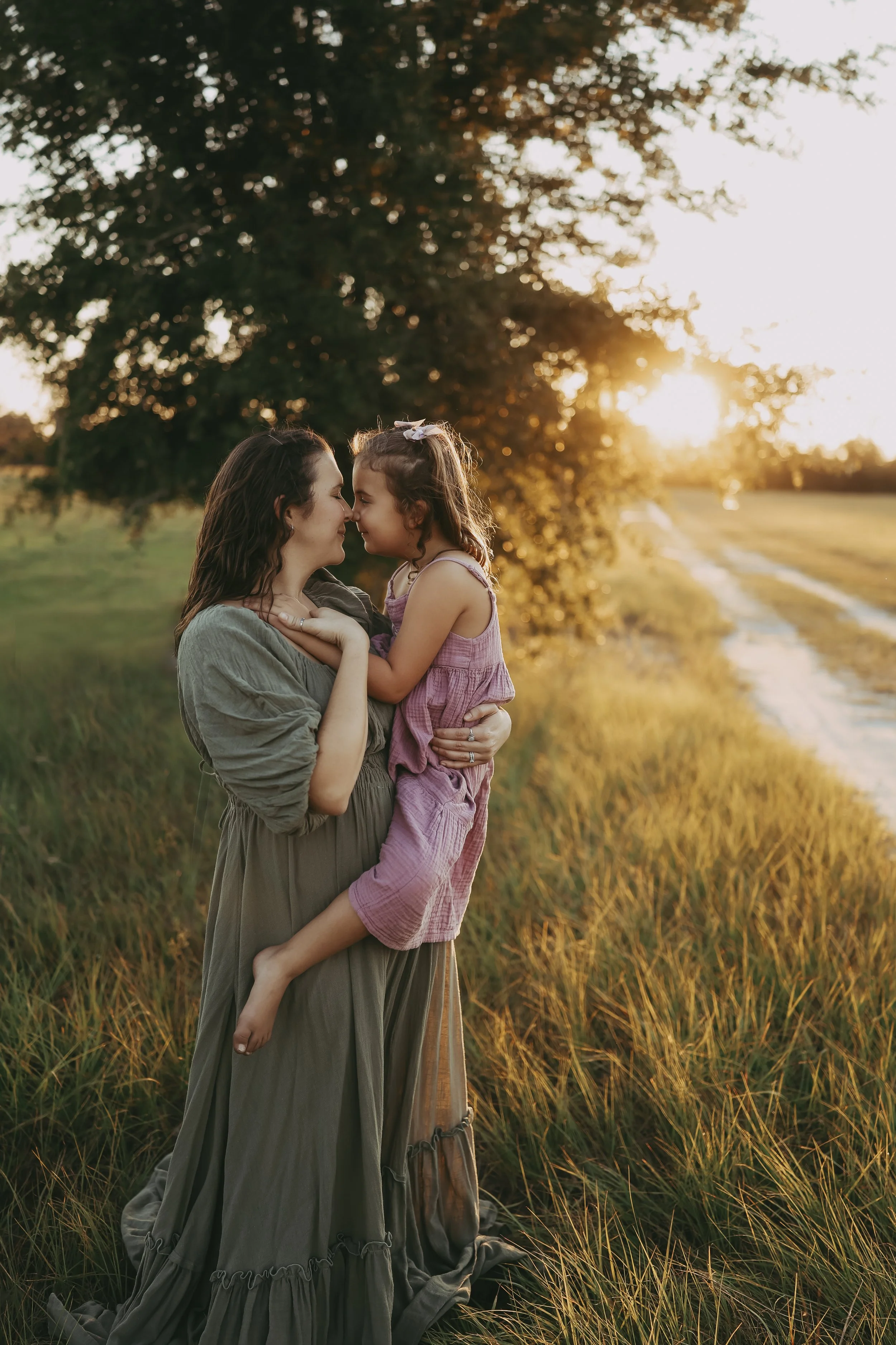 A mother shares a nose-to-nose moment with her daughter during a golden sunset in a peaceful Florida field.