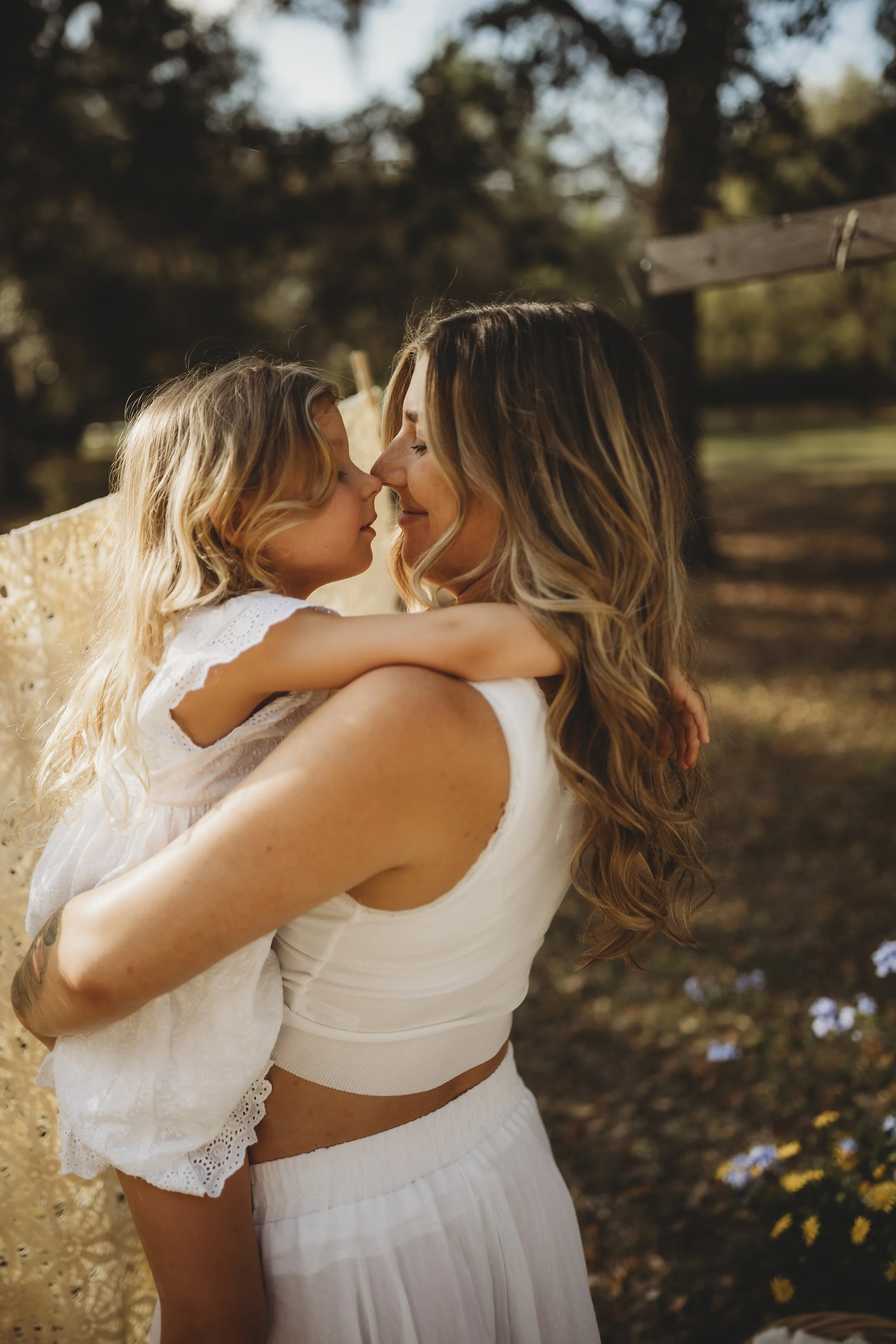 A mother holds her daughter close, their faces inches apart, a moment of connection that speaks to the depth of motherhood and family.
