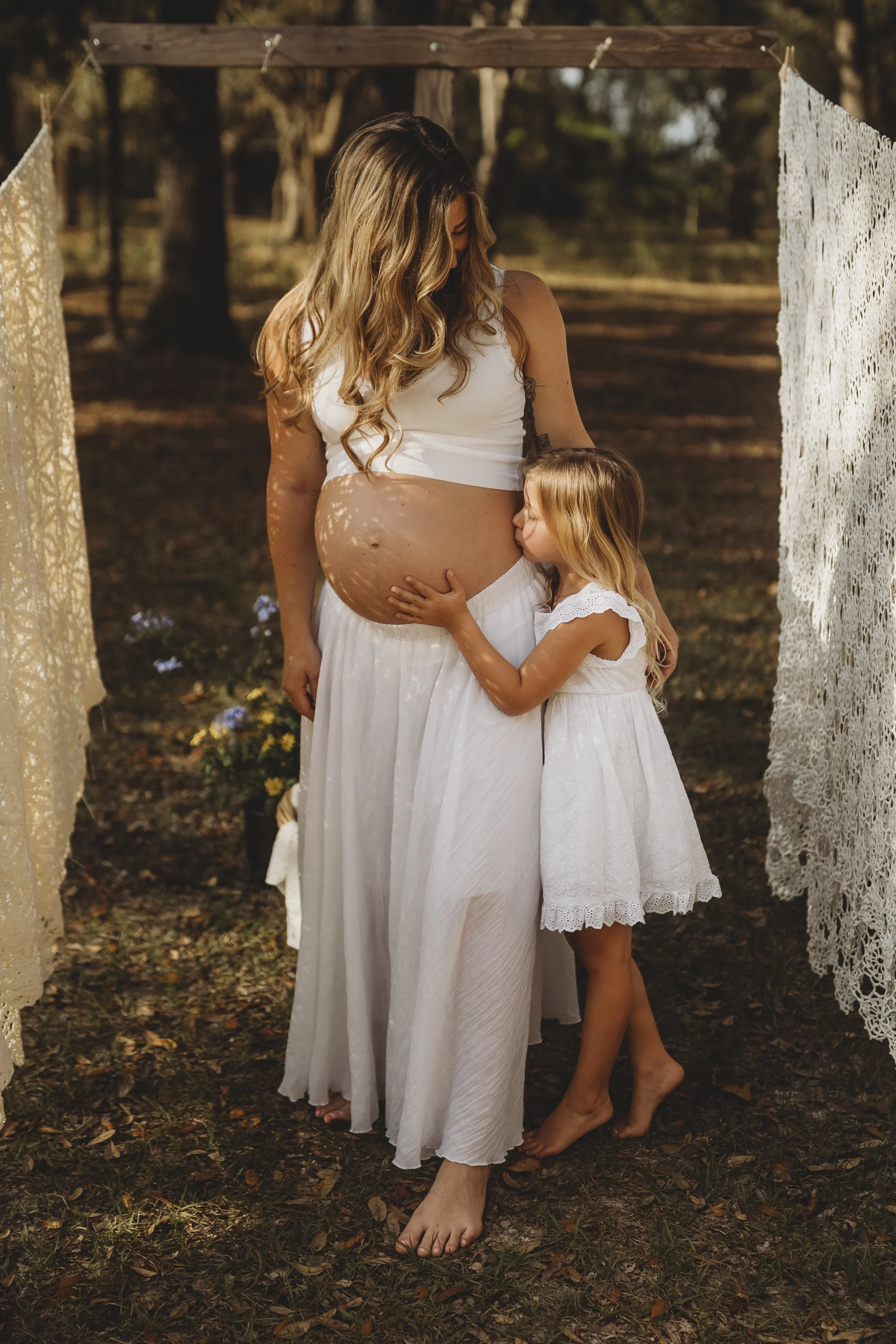 Barefoot and wrapped in warmth, a mother and daughter stand together, hands cradling the promise of what’s to come