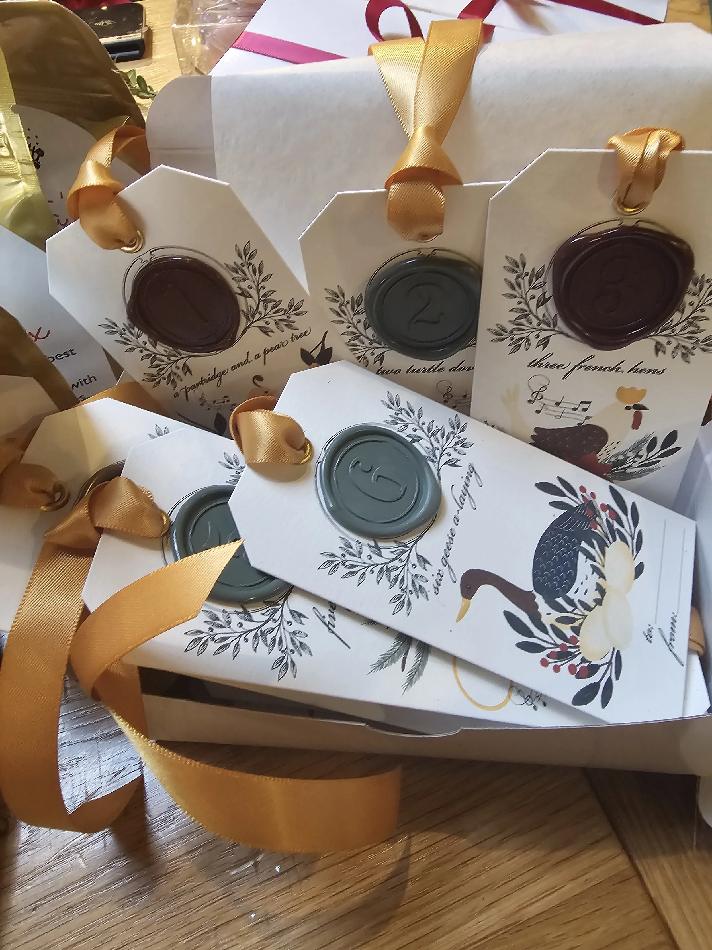 Handmade holiday gift tags with numbered wax seals and gold satin ribbon, luxury Christmas wrapping accents.