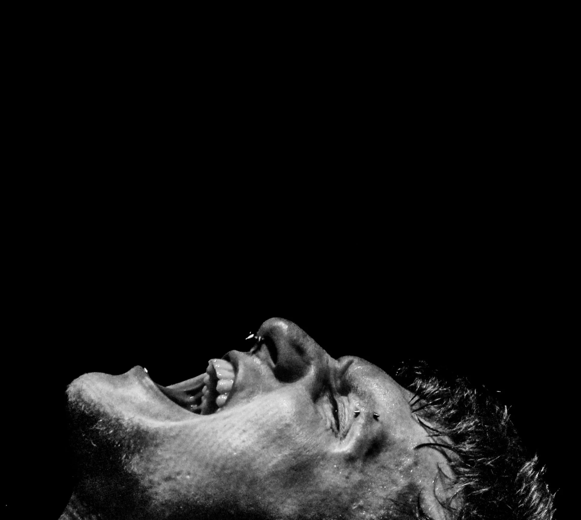 A black and white photo of a man yelling into darkness